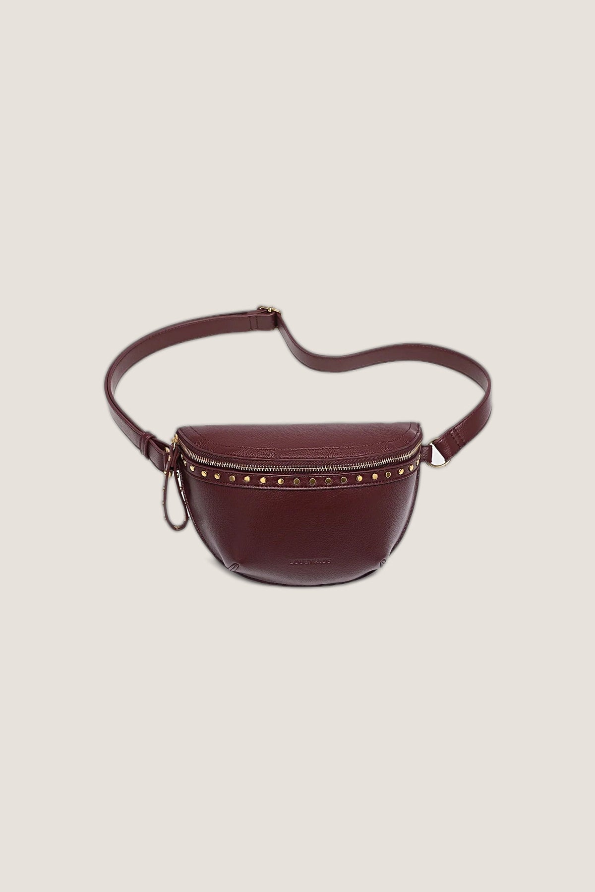 Cassidy Burgundy Belt Bag in pebbled burgundy vegan leather with a row of antique gold studs and gold zip, front view on a warm greige backdrop.