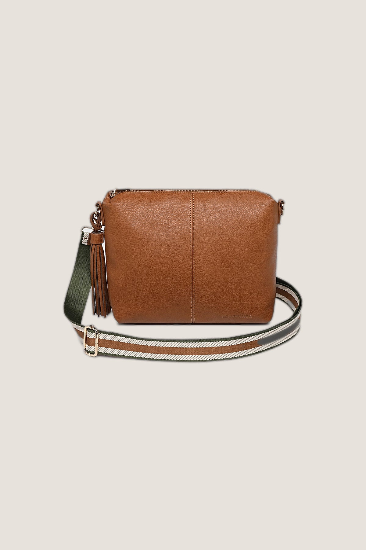 Daisy Stripe Tan Crossbody Bag in tan vegan leather with a tassel and an olive, cream and tan striped webbing strap, front view on a warm greige backdrop.