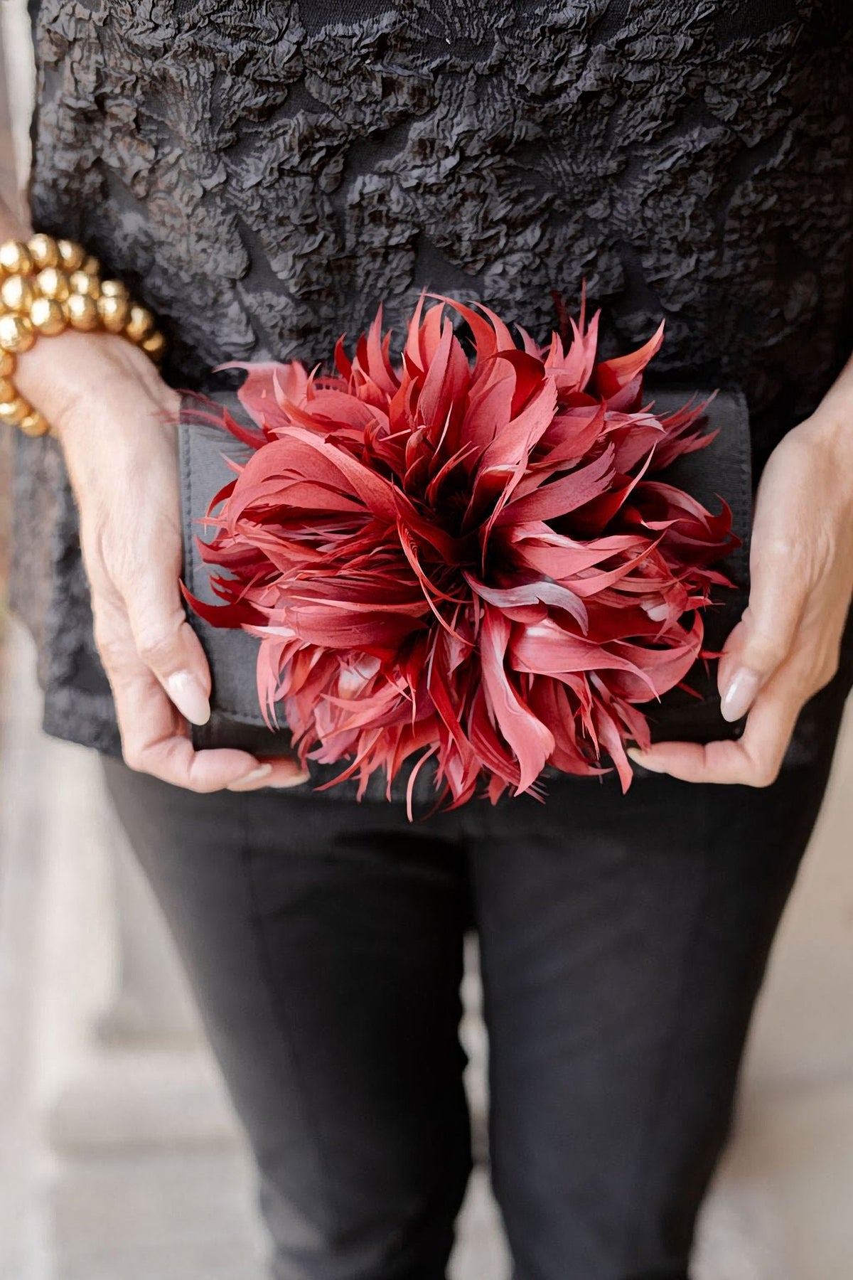 The Black Scallop Ruby Feather Clutch held with a black top and skirt.