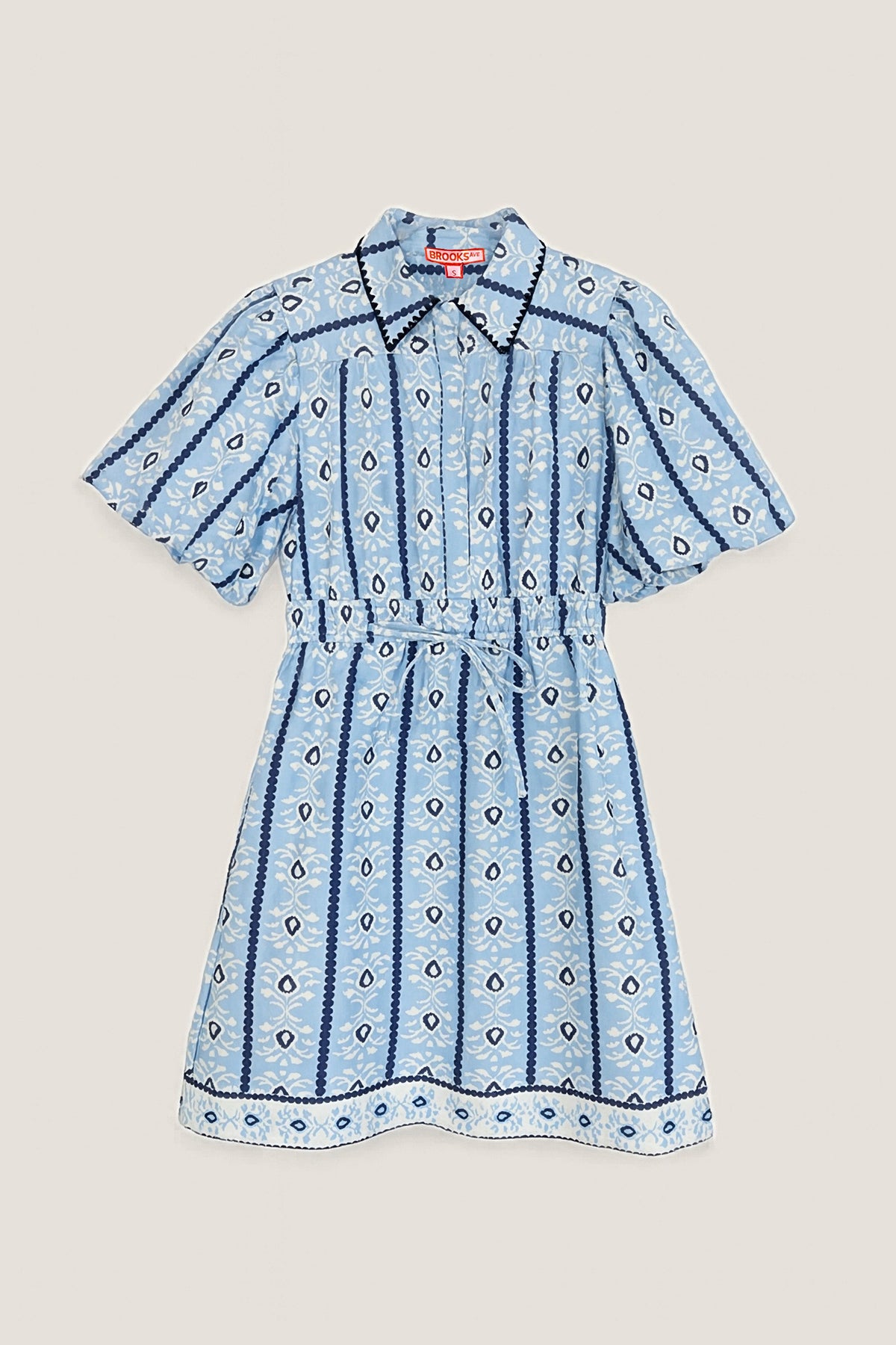 The Banyan mini dress in blue cabana stripe laid flat, showing the collar, puff sleeves and tie waist.