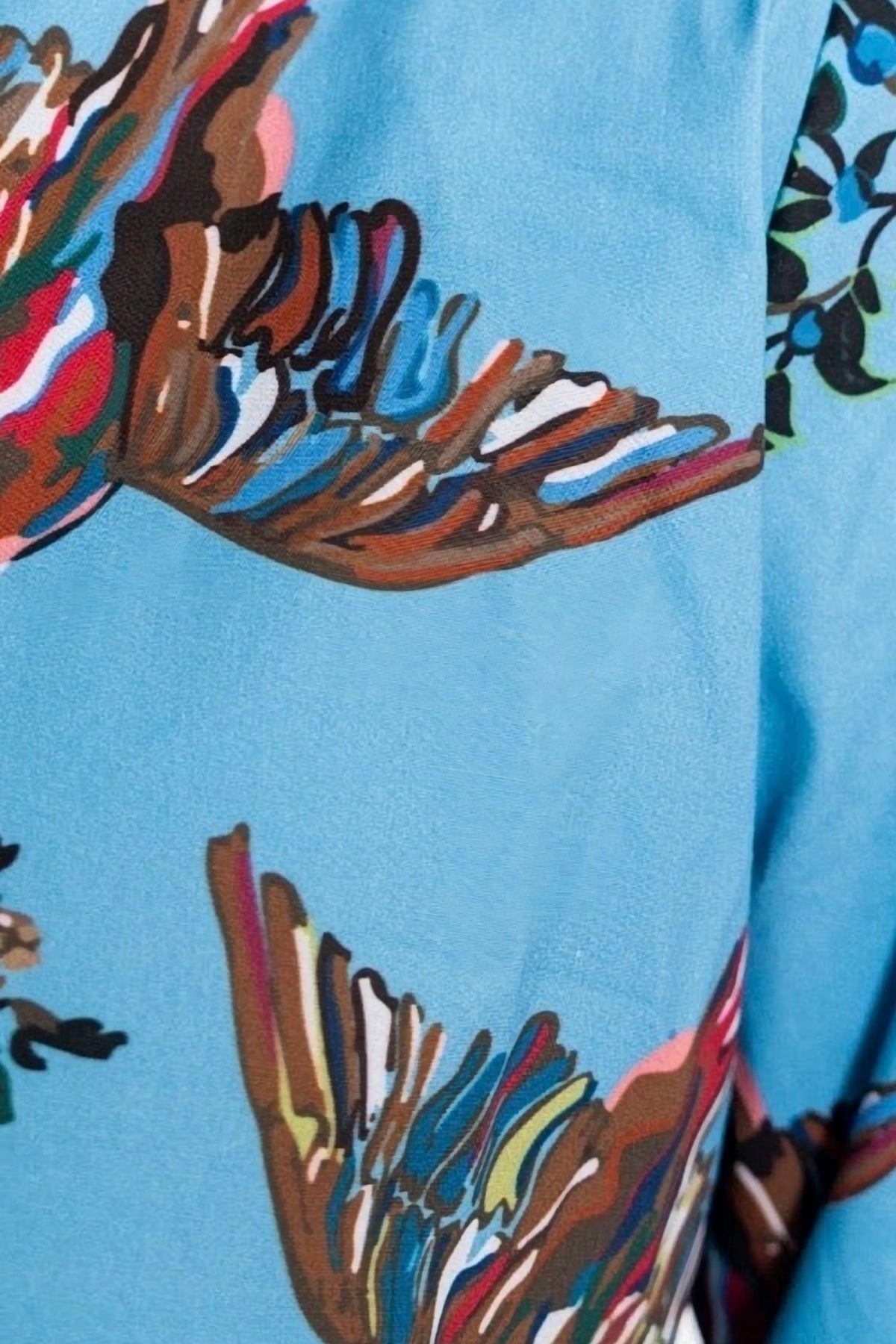 Close-up of the Berry Grove print, colorful birds and branches on sky blue cotton poplin.