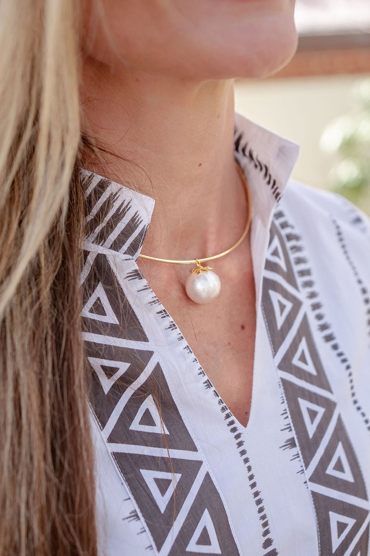 Model wearing the gold Birdie Cotton Pearl Collar Necklace at the collarbone with a patterned white shirt.