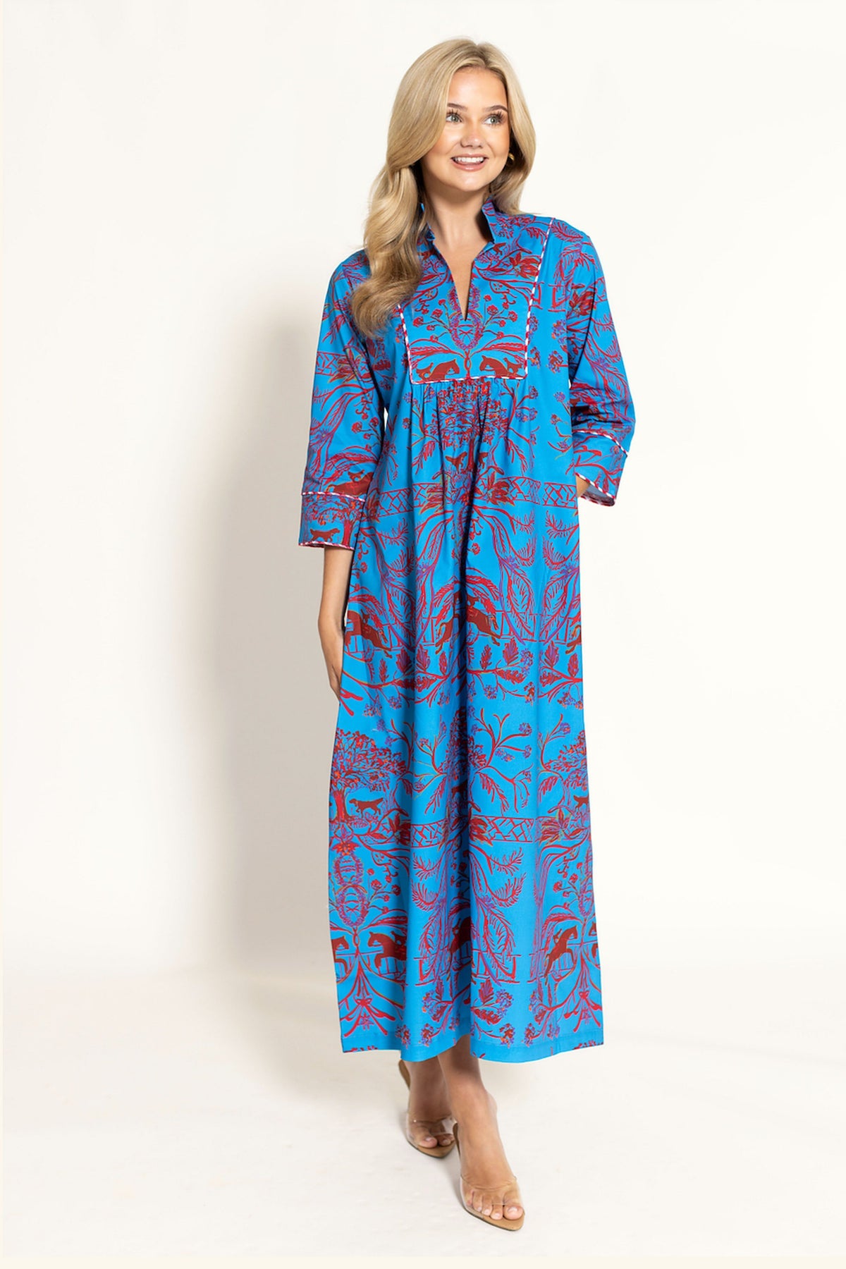 woman in a red and blue maxi dress standnig on an offwhite background