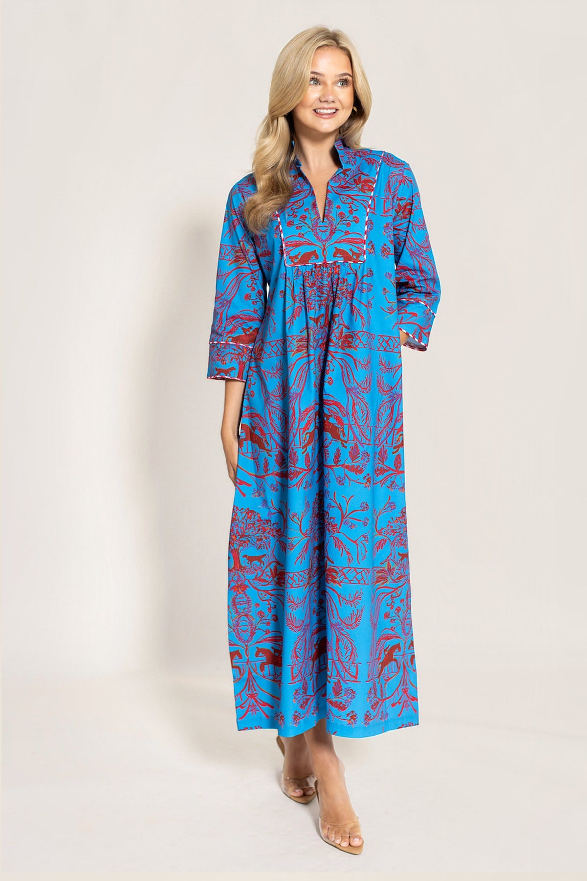 woman in a red and blue maxi dress standnig on an offwhite background