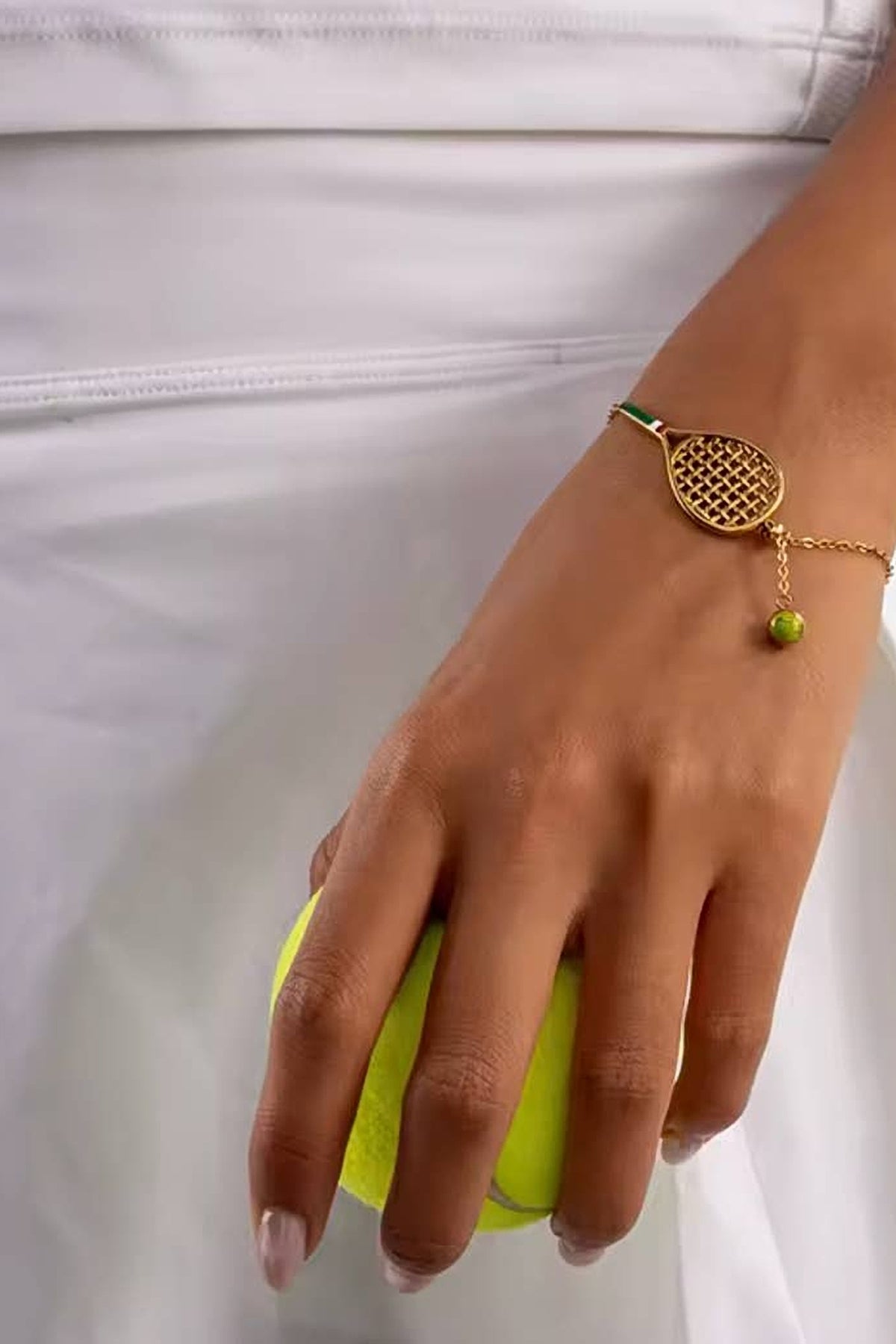 The Country Club tennis bracelet on the wrist, hand holding a tennis ball.