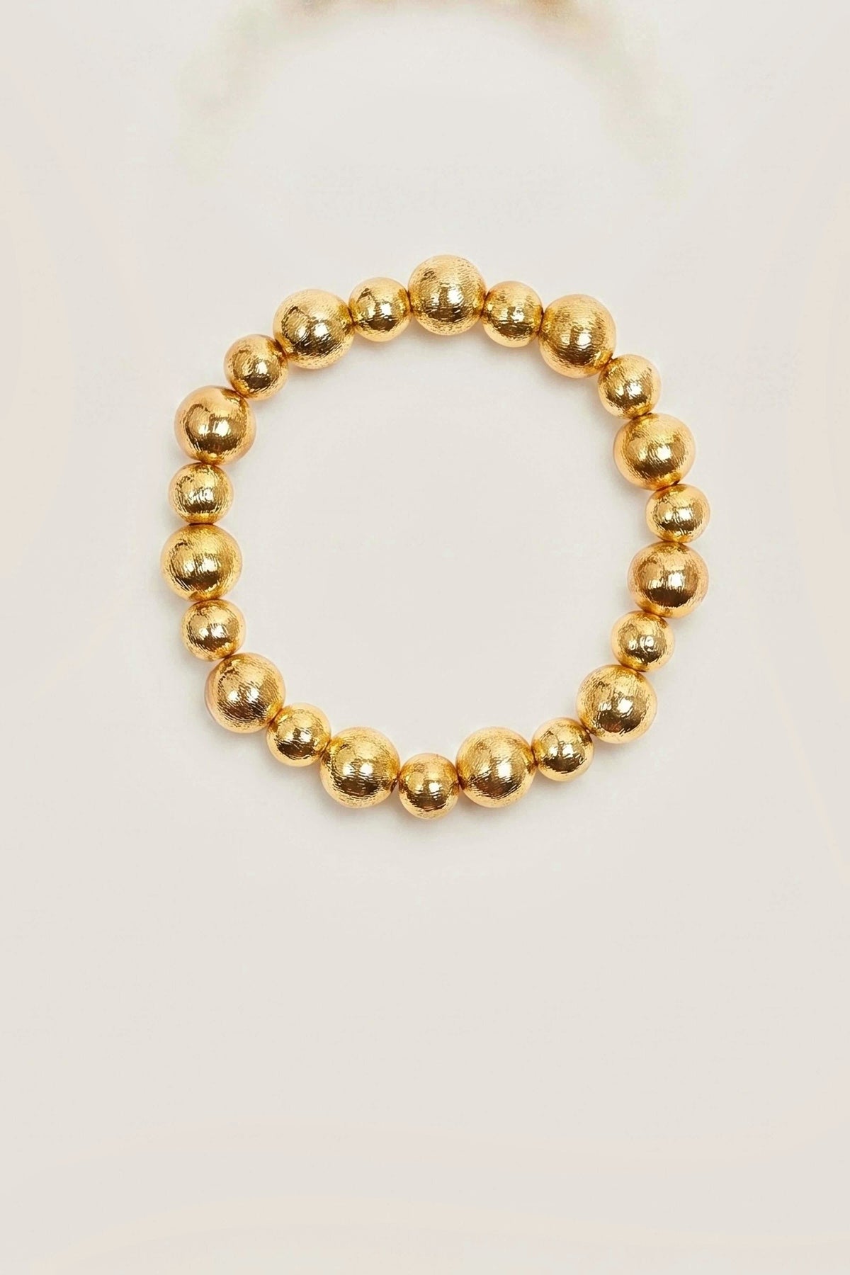 Georgia Gold Beaded Bracelet by Lisi Lerch, a stretch bracelet of mixed 10mm and 8mm gold beads, on a warm greige backdrop.