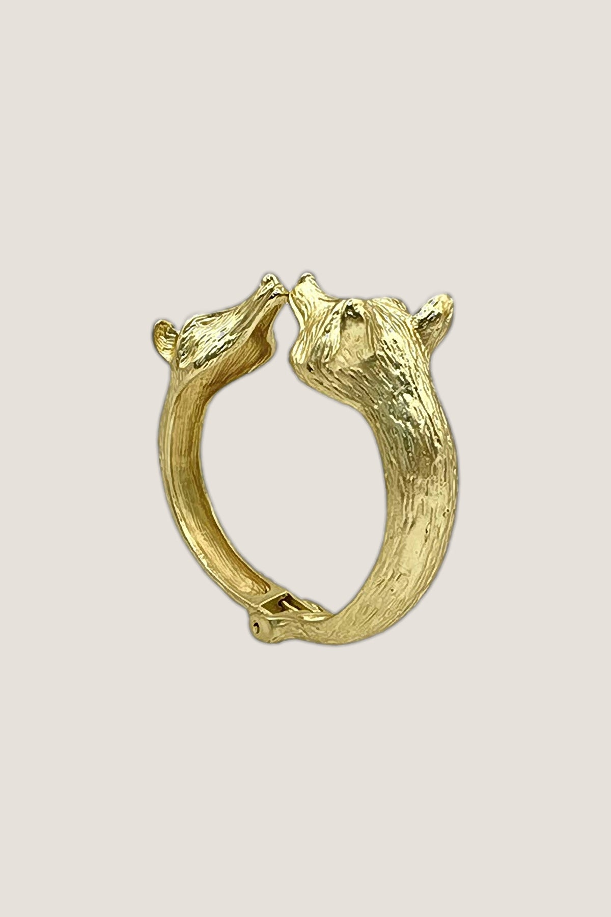 Three-quarter view of the Golden Fox Hinged Bracelet, showing the textured band and the two fox heads.