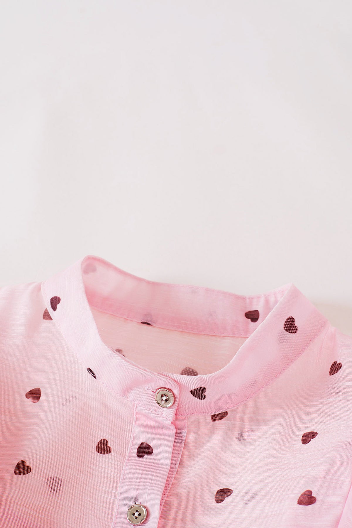 Close-up of the stand collar and covered front buttons on the heart print organza top.
