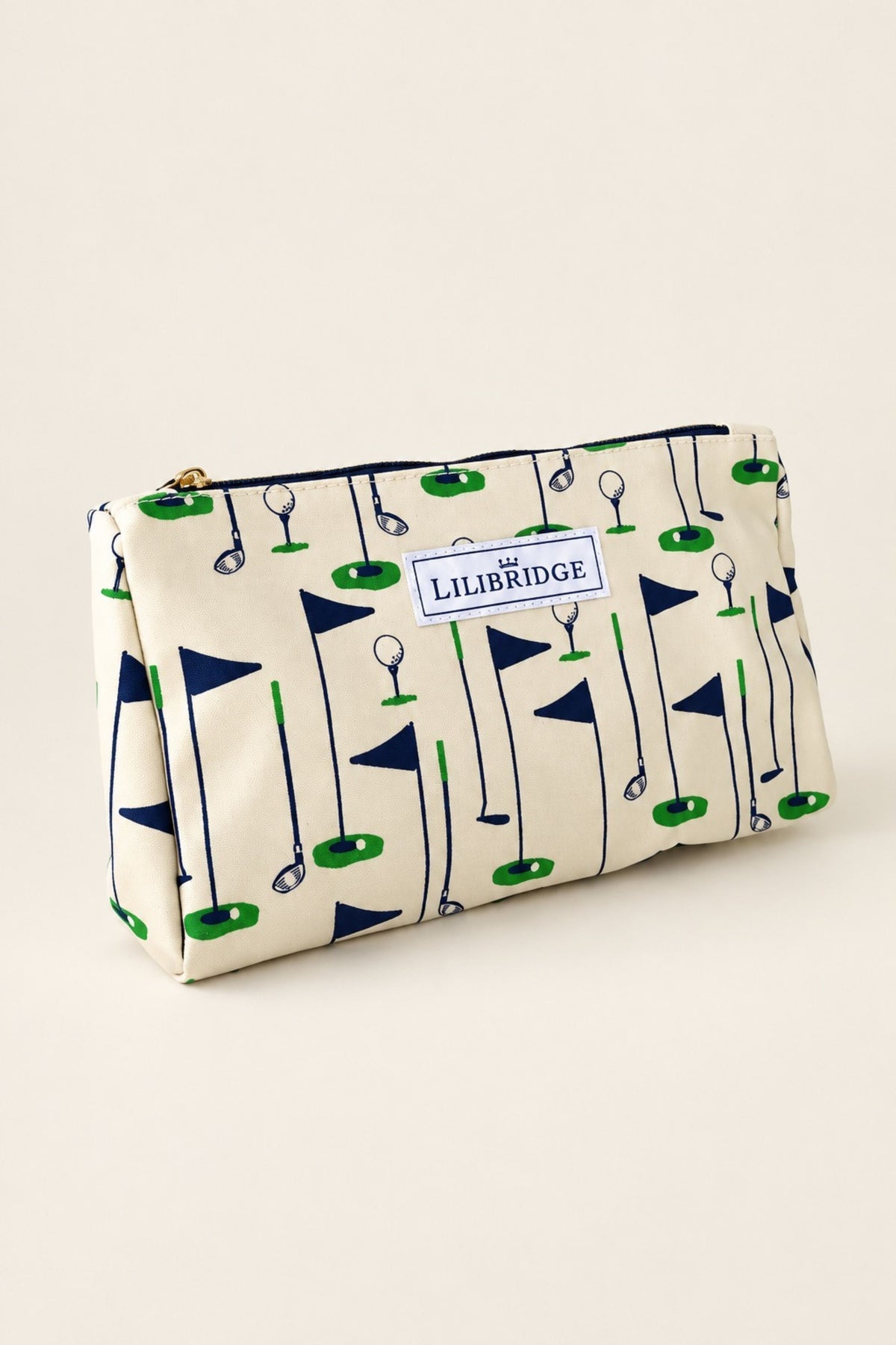 A rectangular zip pouch with a golf-themed print featuring navy blue flags, green golf balls and clubs, and a white label reading 'LILIBURGE' on a cream background, set against a solid beige backdrop.