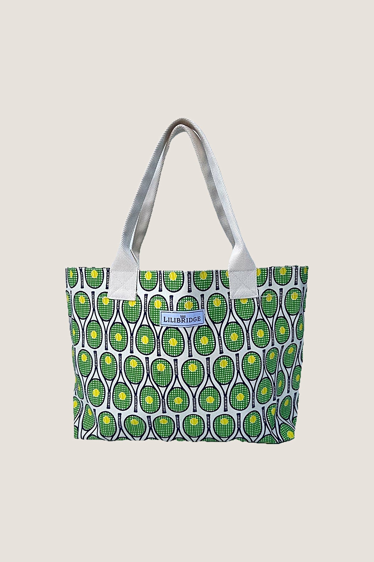 The Live & Love Tote in the Tennis print: green rackets with yellow balls on glossy coated canvas, natural webbing handles, front view.