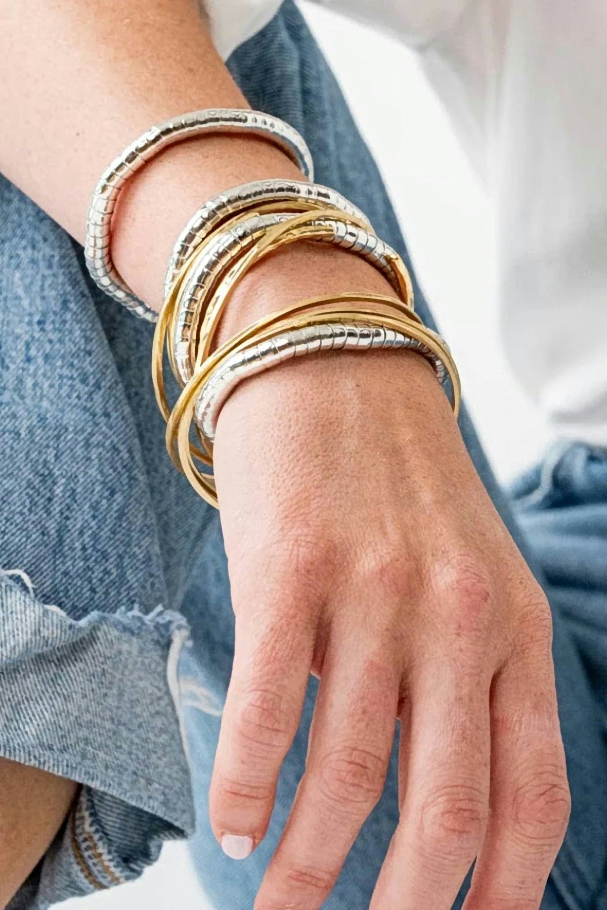 Lucille Round Bead Stretch Bracelets in silver stacked with gold bangles on the wrist.