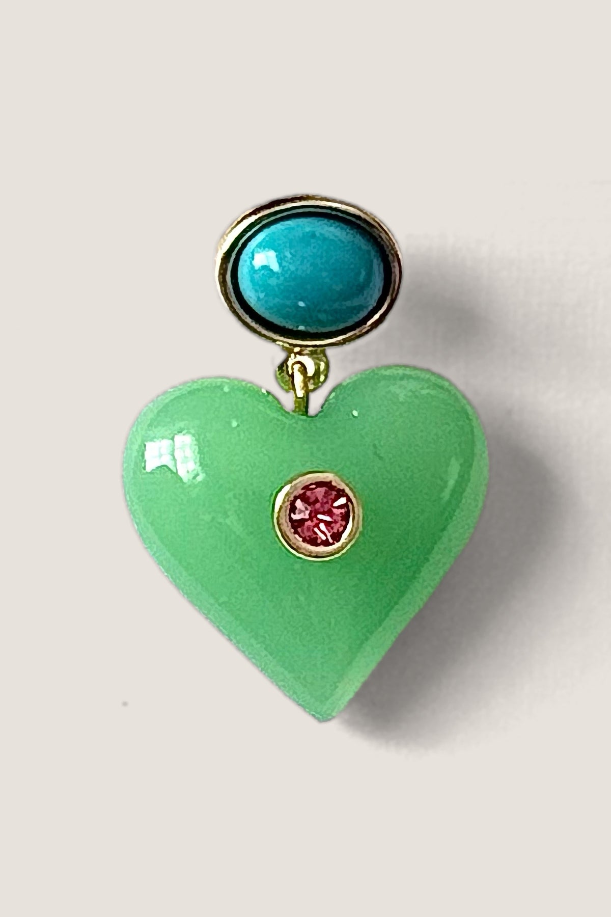Close-up of one Lucky Heart earring showing the turquoise cabochon, the jade green heart and the pink crystal set in gold.