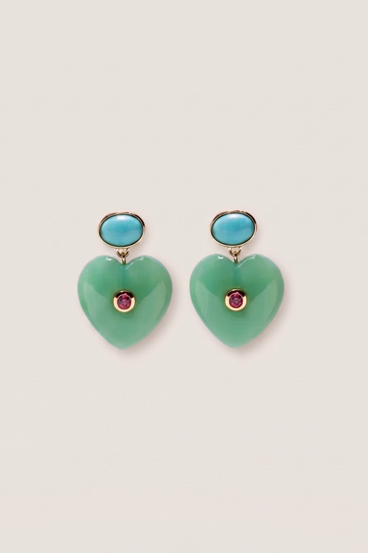 A pair of heart-shaped drop earrings featuring light green stone pendants with a small round pink gemstone at the center, suspended from gold-toned posts topped with oval light blue stones, set against a plain off-white background.