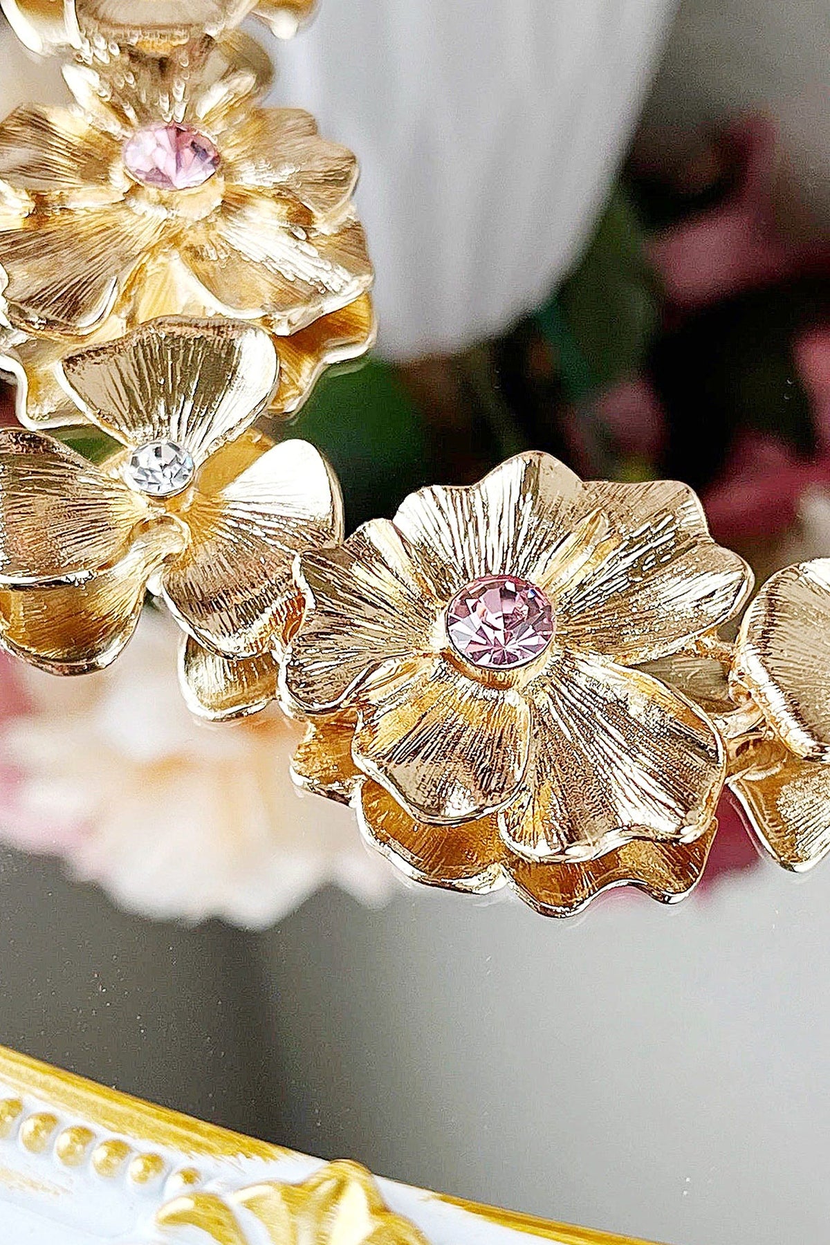 Close-up of the brushed gold flowers and pink crystal centres on the Meadow statement necklace.
