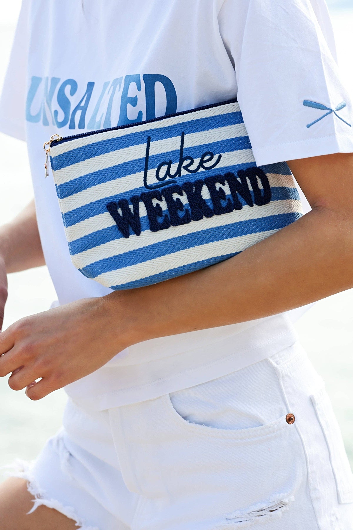 The Morgan Lake Weekend pouch held under the arm, close on the embroidered lettering.