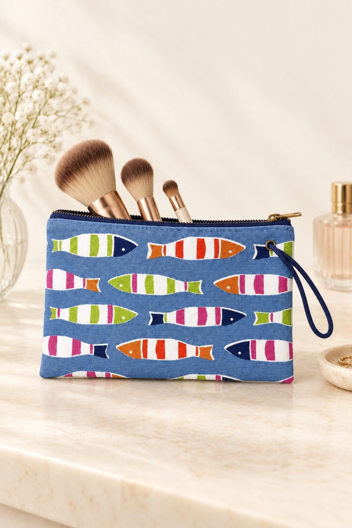 The Picket Fish wristlet standing on a bathroom vanity with makeup brushes tucked inside.
