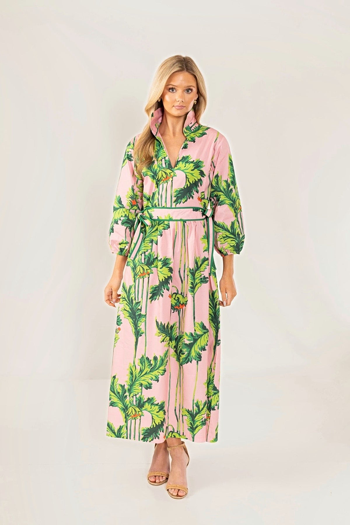 Front view of the Pink Regency long dress in a pink and green palm print with a tie waist.
