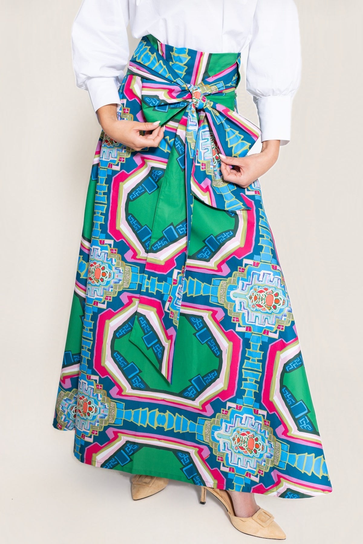 Close-up of the Portico Brady wrap maxi skirt's self-tie waist sash being tied, showing the green, blue and pink architectural Portico print.