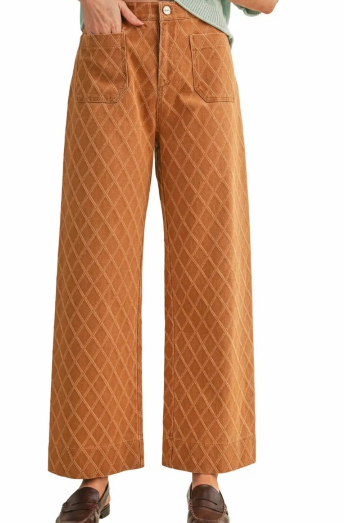 A person wearing wide-leg cropped pants in a warm camel-brown color with a subtle diamond quilted pattern, paired with brown leather loafers and a light green top, shown against a plain white background.