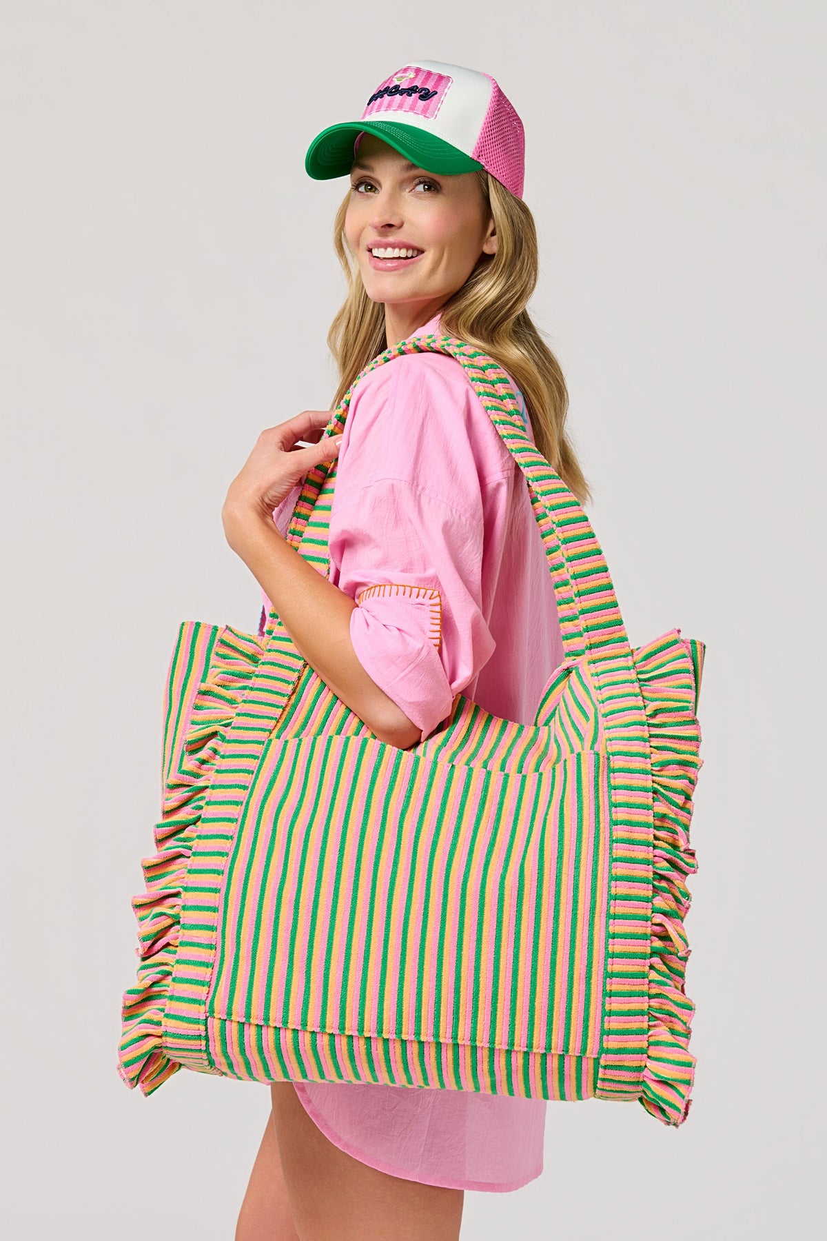A woman in a pink shirt and cap carrying the Sirena Tote on her shoulder.