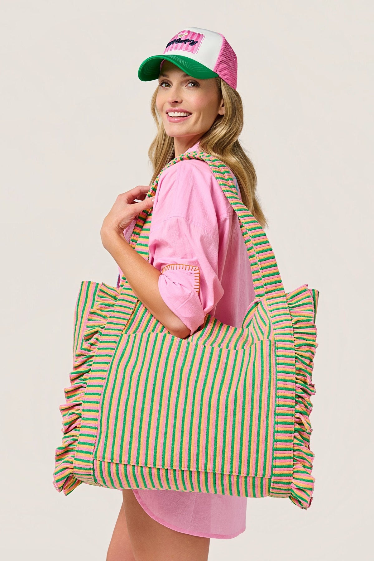 A woman in a pink shirt and cap carrying the Sirena Tote on her shoulder.