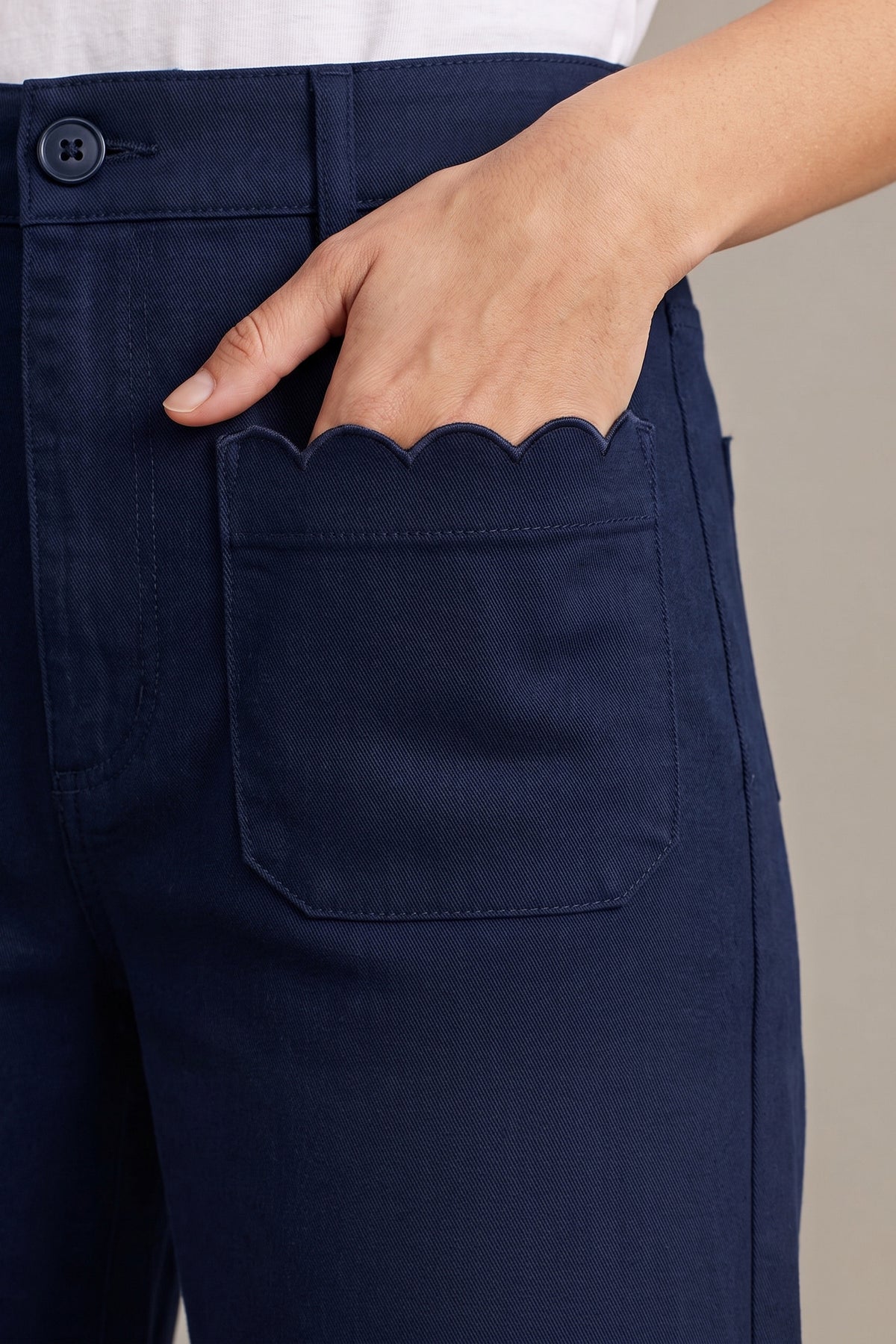 Close-up of the scalloped front patch pocket and button waistband on the navy Maribel pants.