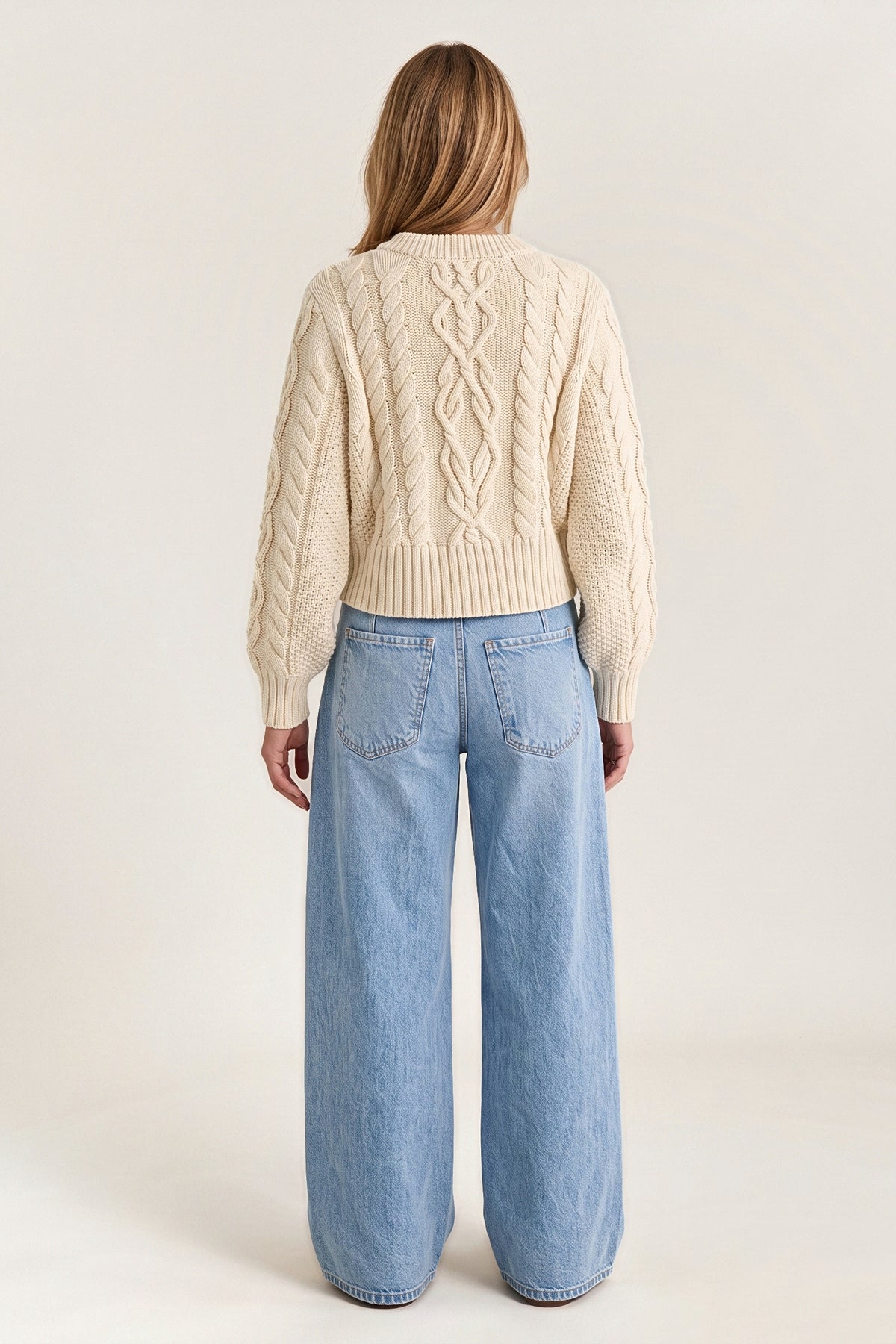Back view of the ecru Newport cable cardigan: a braided centre cable, rope cables, balloon sleeves and a ribbed hem.