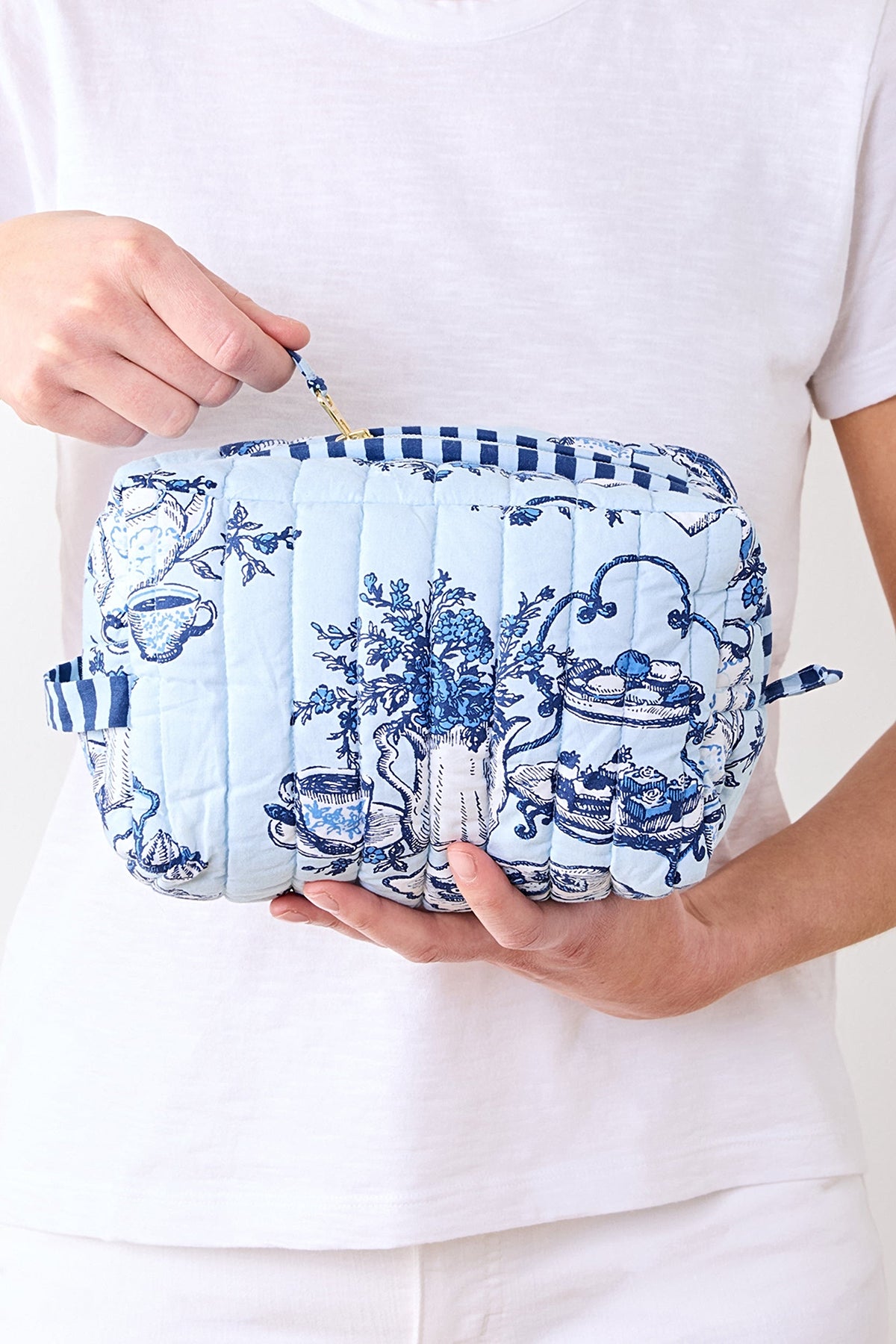 The large High Tea toile pouch held in two hands, showing its size against the body.