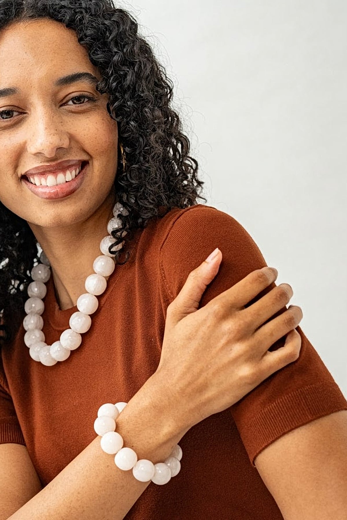 Smiling model wearing the milky white Iris resin bead necklace with a matching white bead bracelet.
