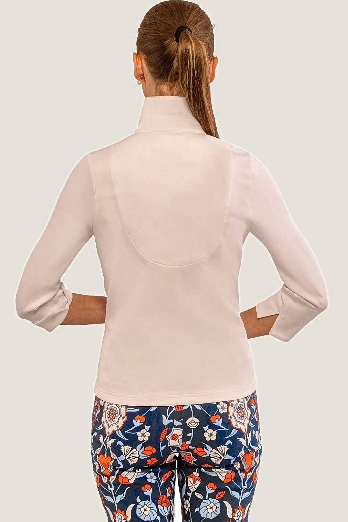 Woman wearing a white jersey top and floral pants on a white background
