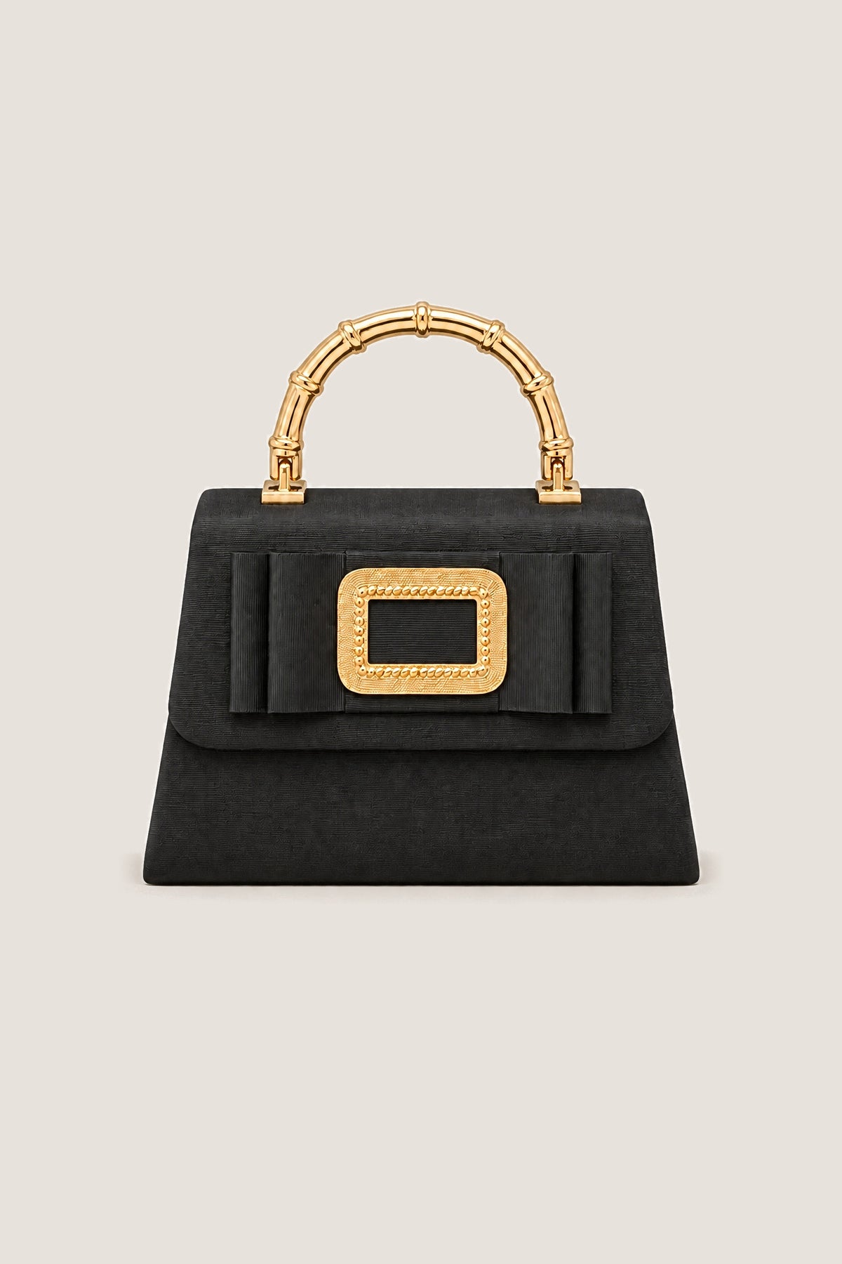 Black Lulu bag in black faille with a flat bow, gold buckle and gold bamboo-style handle, front view on a warm greige backdrop.