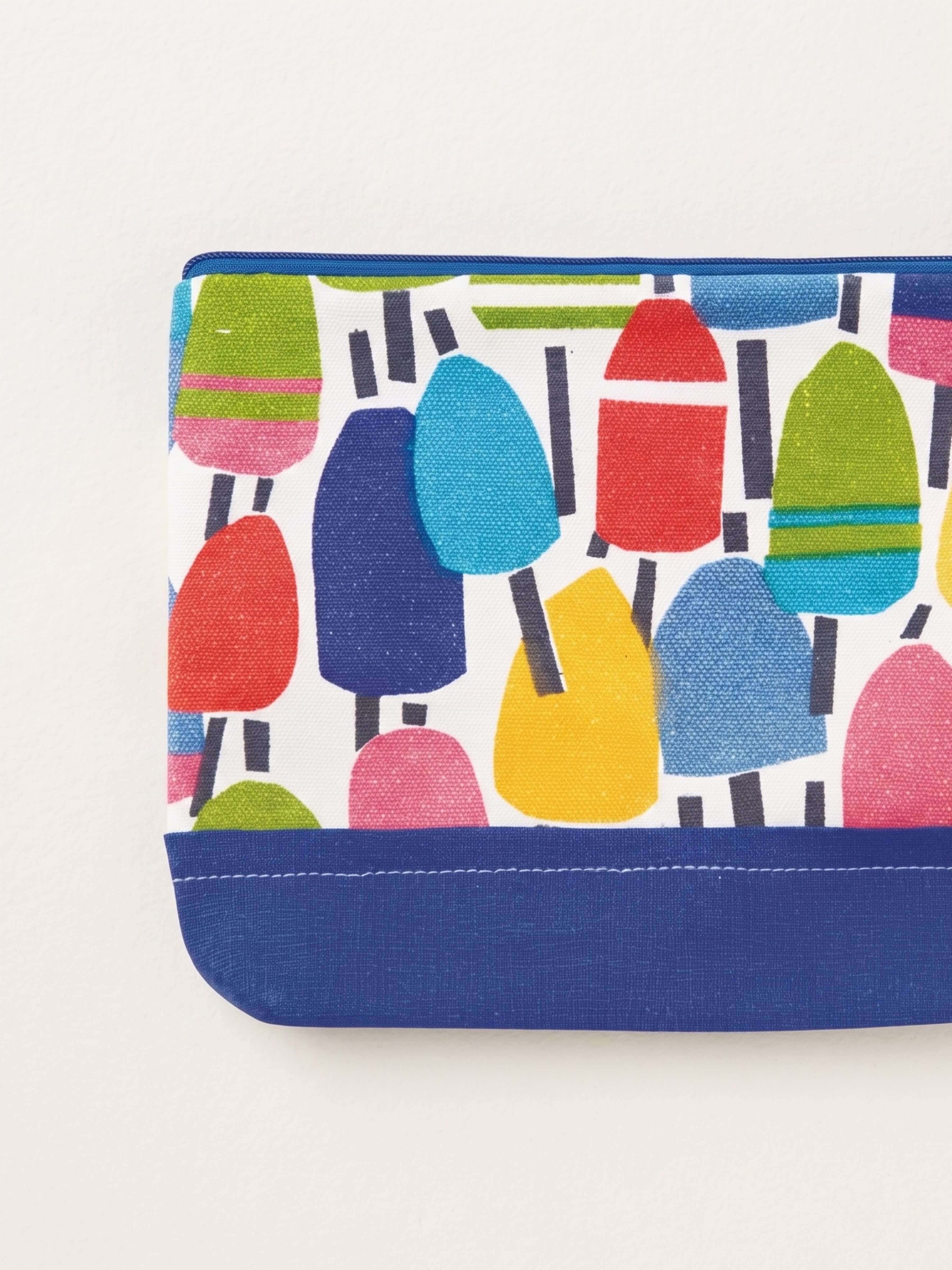 A close-up of a fabric pouch or clutch with a colorful popsicle print on a white background and a solid navy blue bottom border, photographed on a light off-white background.