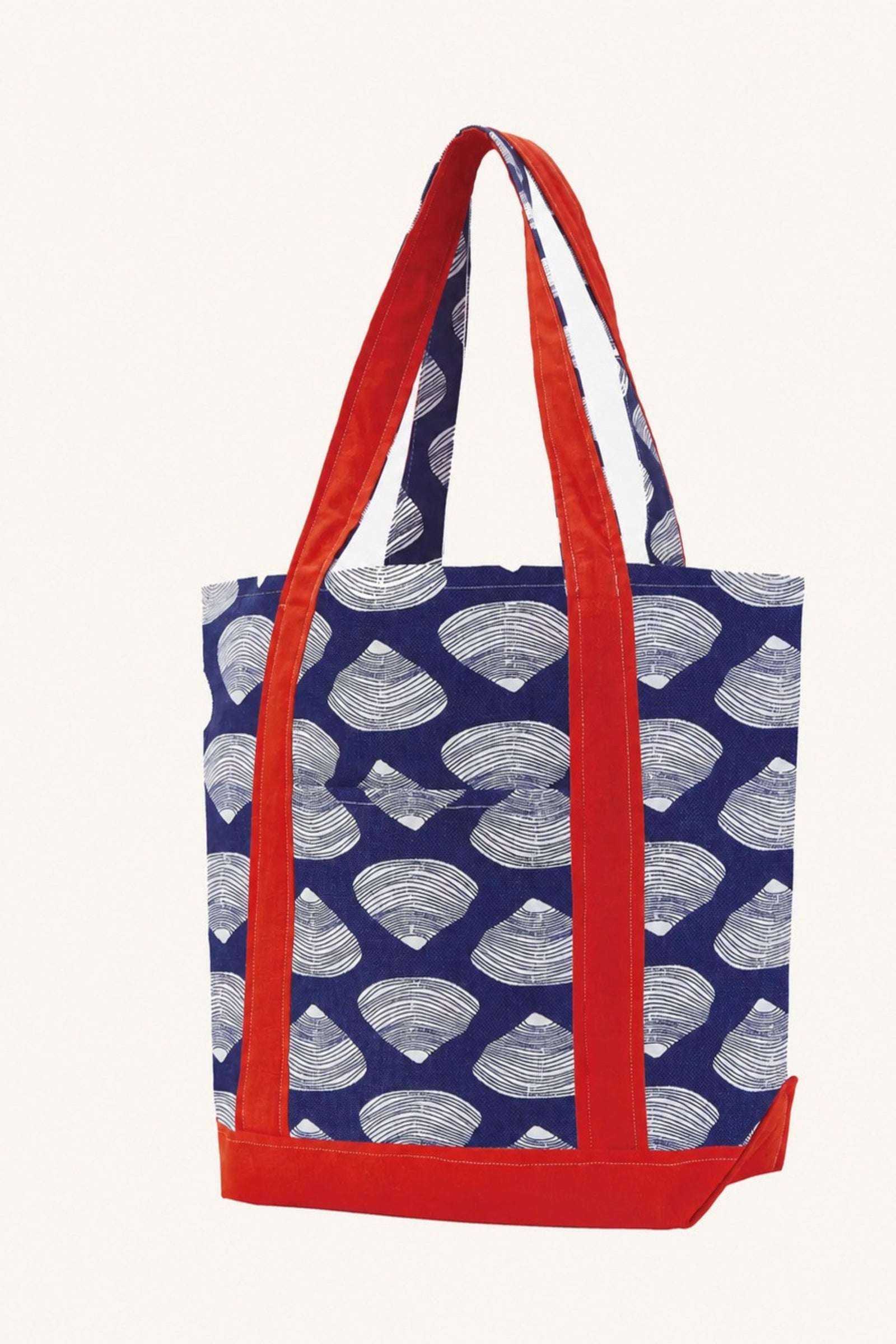 A canvas tote bag with a navy blue and white scallop shell pattern, featuring bright red handles and a red bottom base, shown against a plain off-white background.