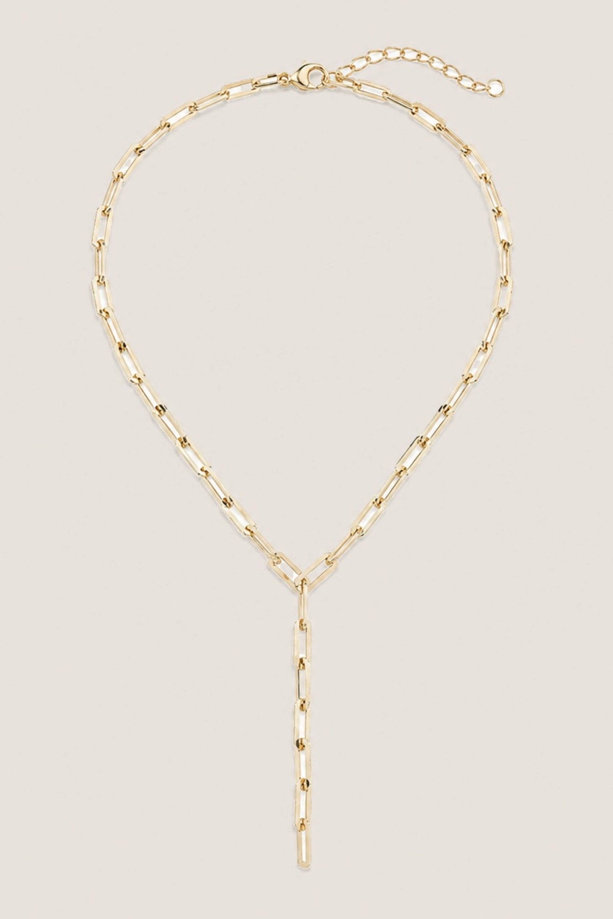 A gold paperclip chain necklace with a long vertical dangle pendant, displayed on a clean off-white background.