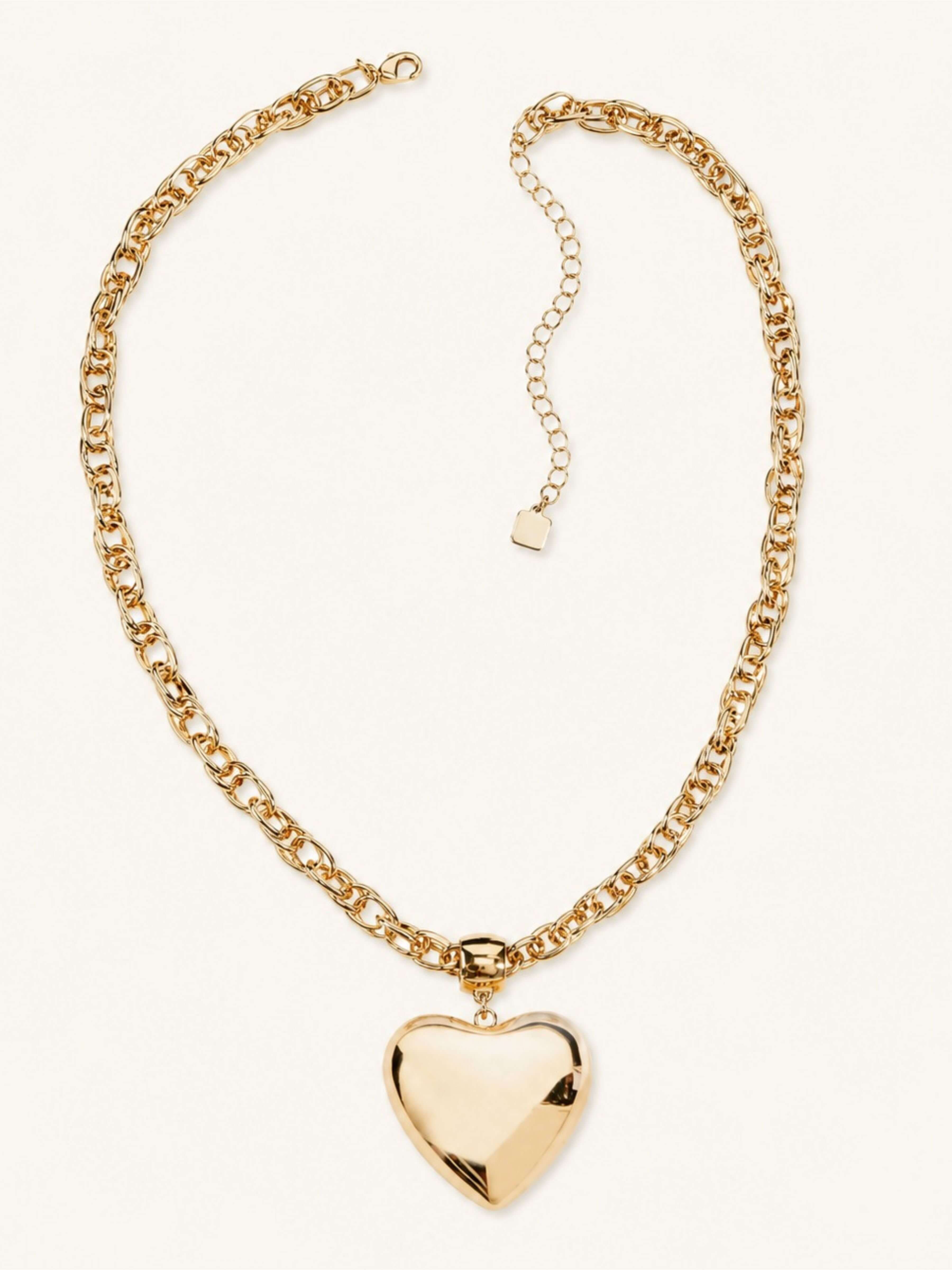 A gold chain necklace with a polished, faceted heart-shaped pendant, displayed on a clean off-white background.