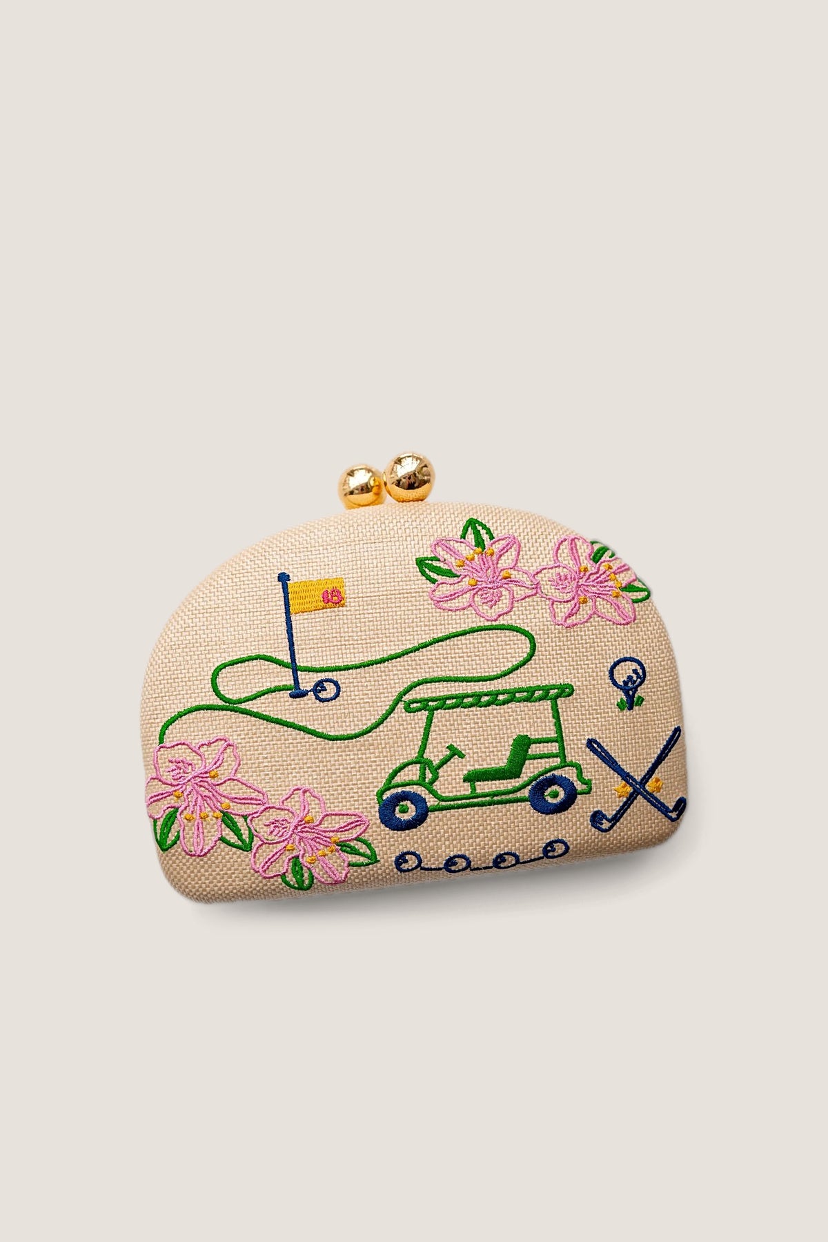 The Lisi Lerch Golf Embroidered Clutch in natural straw, embroidered with a golf cart, pink blossoms, a flag and crossed clubs, shown front on with its gold ball clasp.