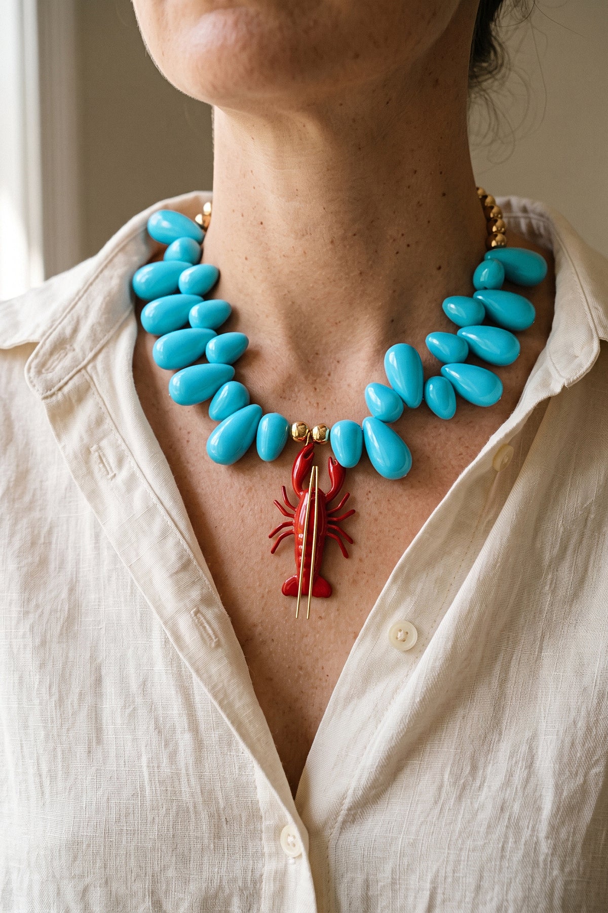 Lobster Kitsch and Sea necklace worn at the collarbone with a cream linen shirt