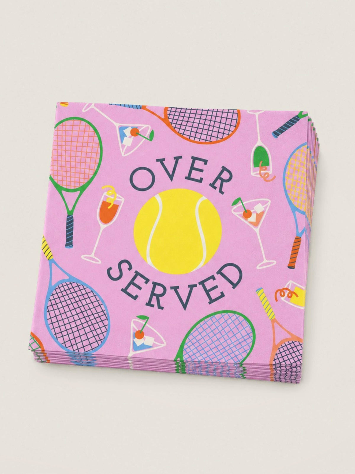 A stack of pink paper napkins featuring a tennis-themed pattern with rackets, a yellow tennis ball, cocktail glasses, and the words 'OVER SERVED' in dark lettering, shown on a light beige background.