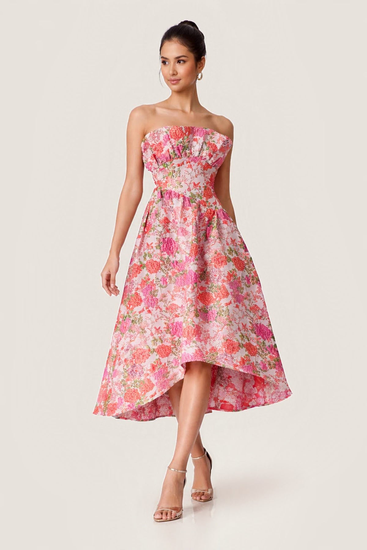 A woman walking in the strapless pink floral jacquard Rosemont High-Low Dress, three-quarter view showing the ruched neckline and high-low hem