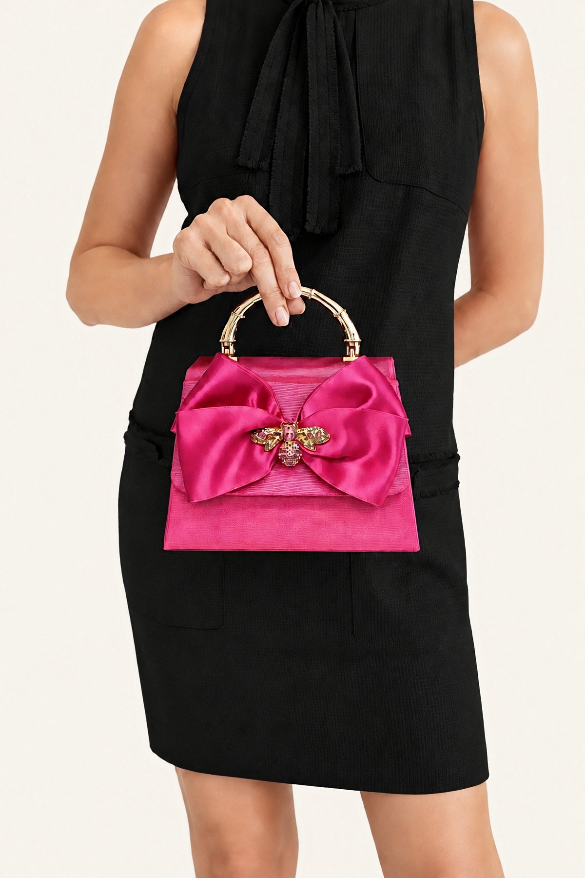 The Pink Lulu handbag carried by its handle with a black sleeveless dress.
