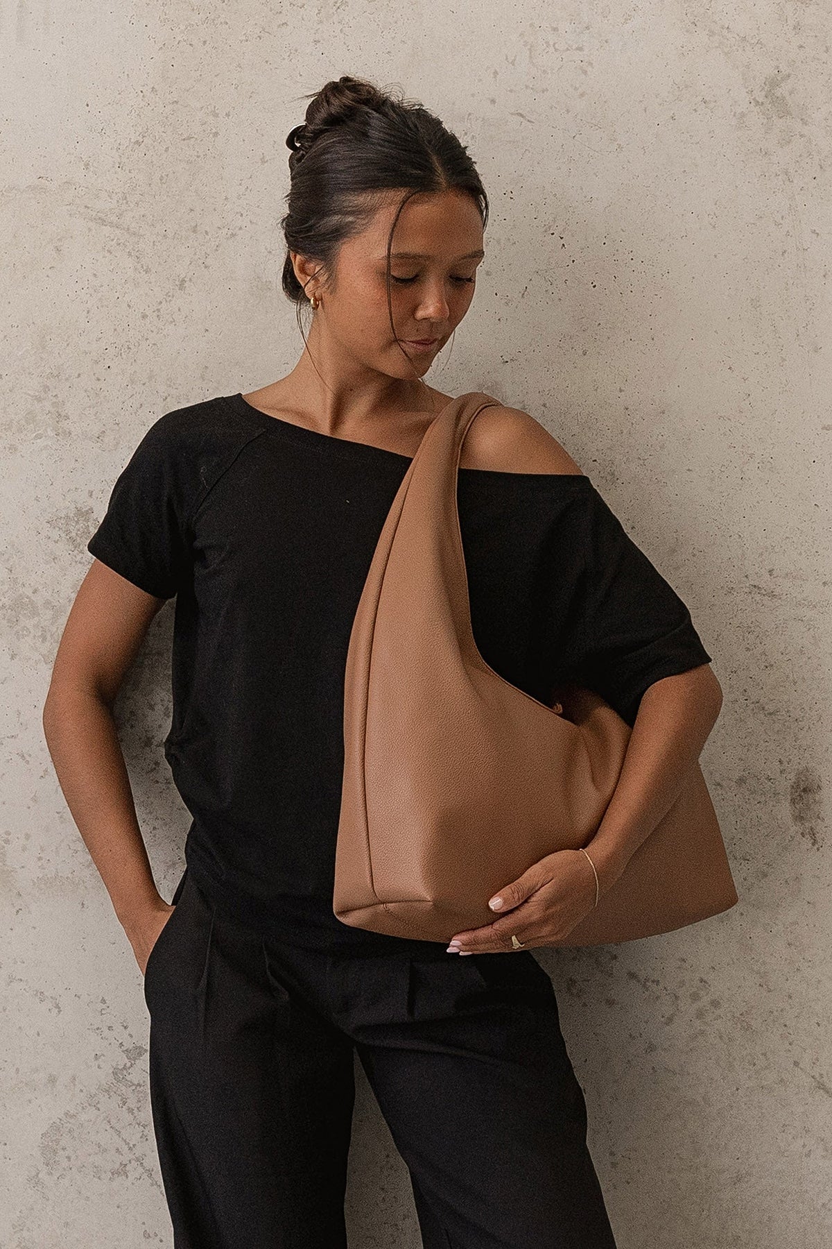 The Monaco Toffee Shoulder Bag worn under the arm with a black off-shoulder top and black trousers.
