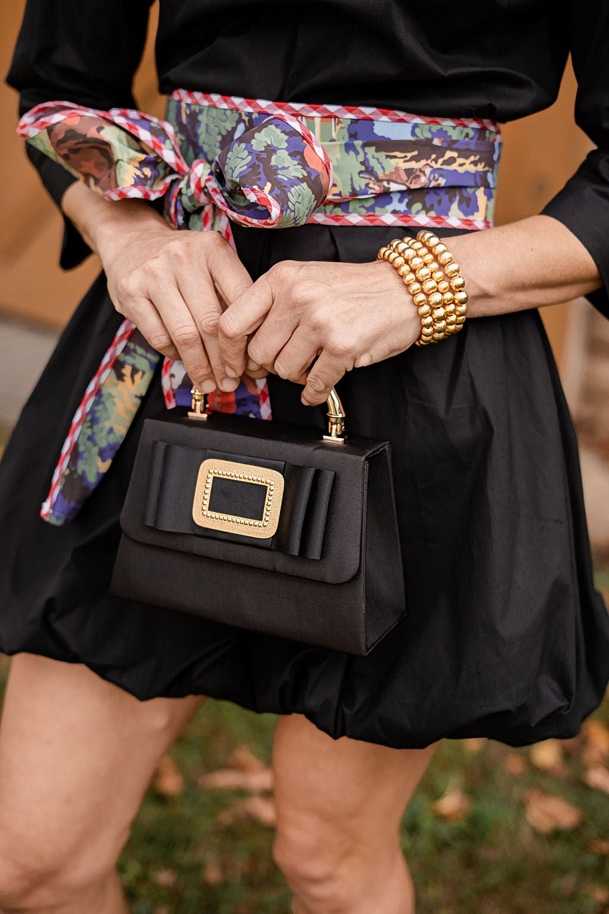 The Black Lulu bag held with a black skirt and a printed scarf belt.