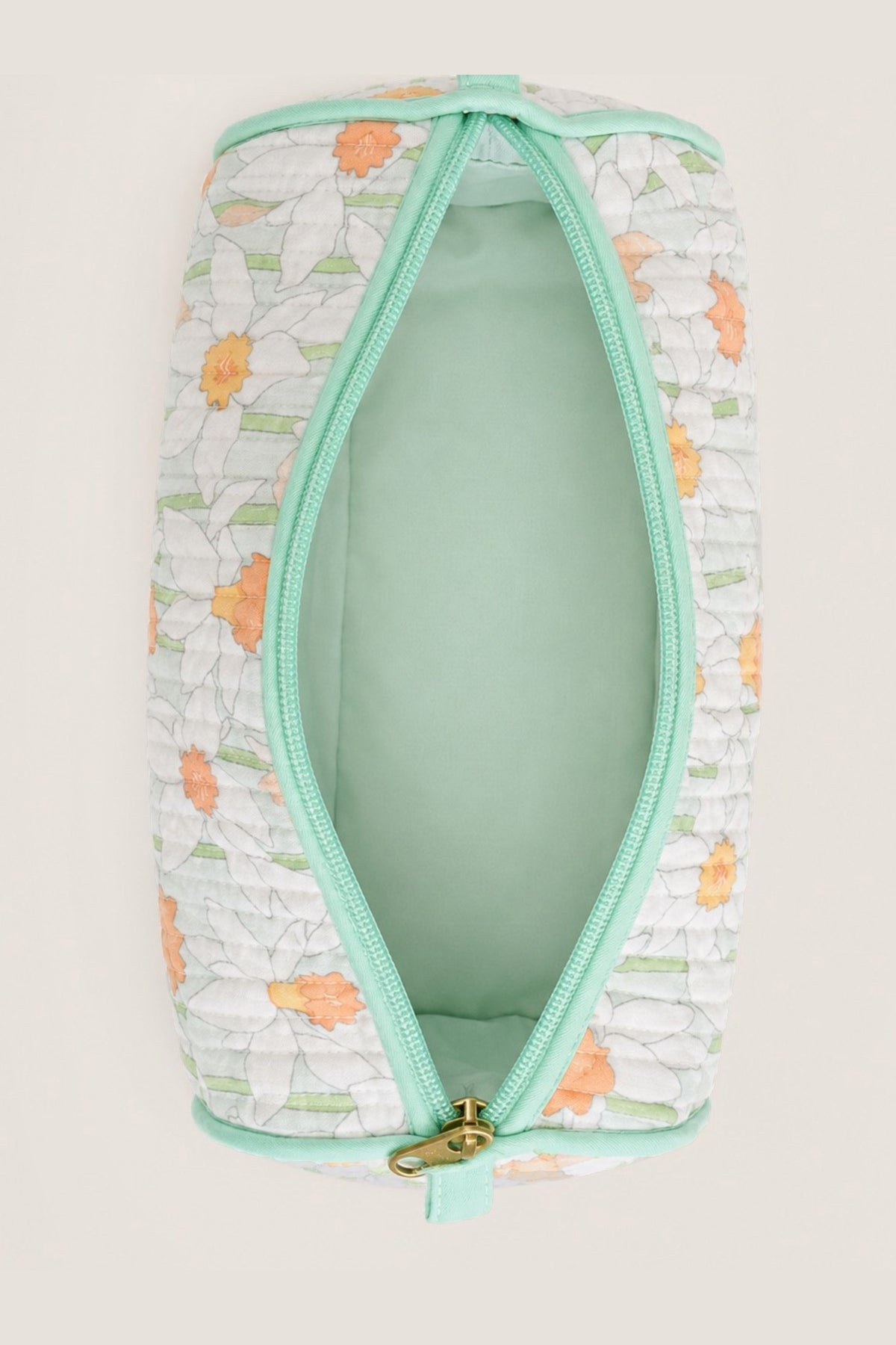 A quilted cosmetic pouch with a white background, orange and green floral pattern, and mint green trim, shown open to reveal a mint green interior.
