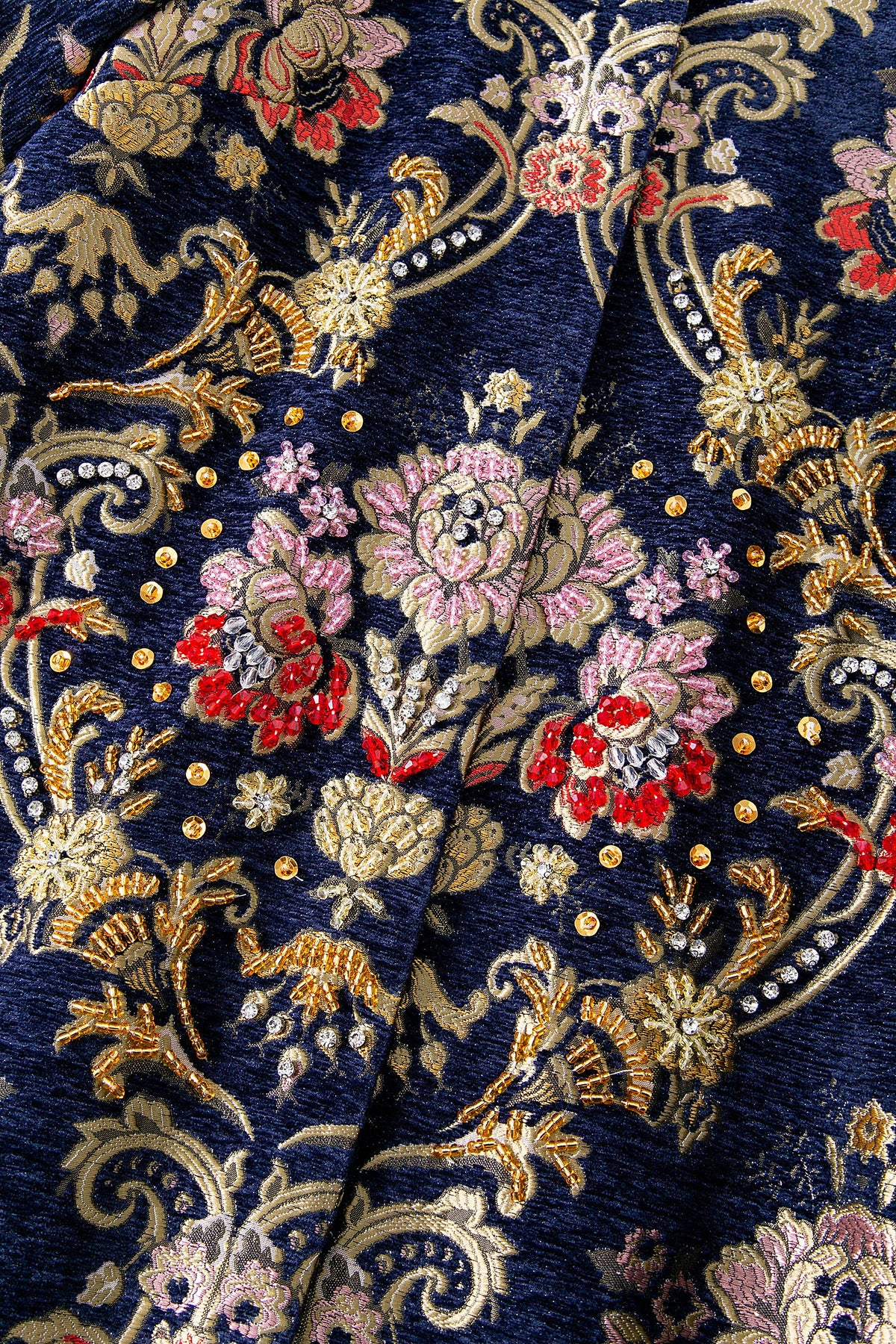 Close-up of the Artisan Studded Corduroy Long Coat brocade with hand-applied gold studs, beading and pink and red floral embroidery