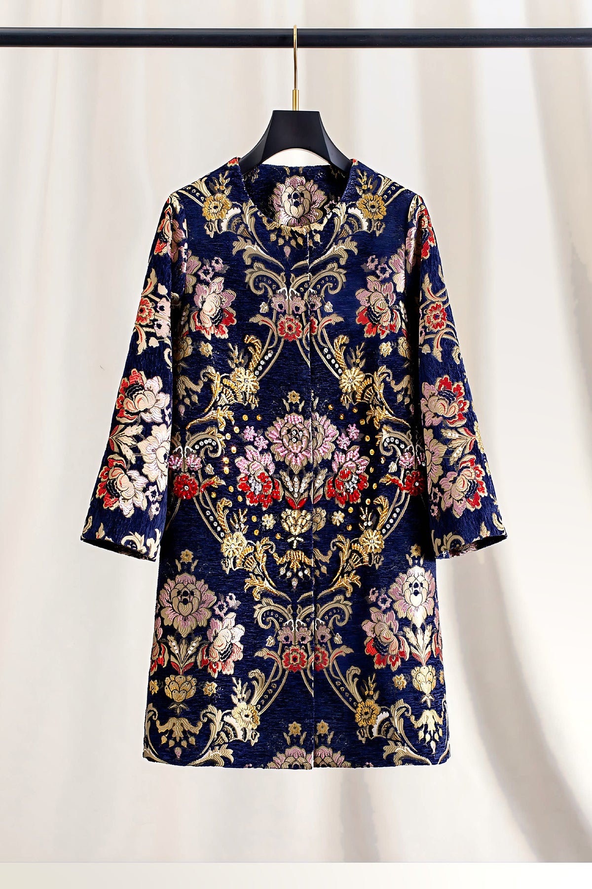The Artisan Studded Corduroy Long Coat alone on a hanger, showing the navy corduroy brocade with pink, red and gold florals