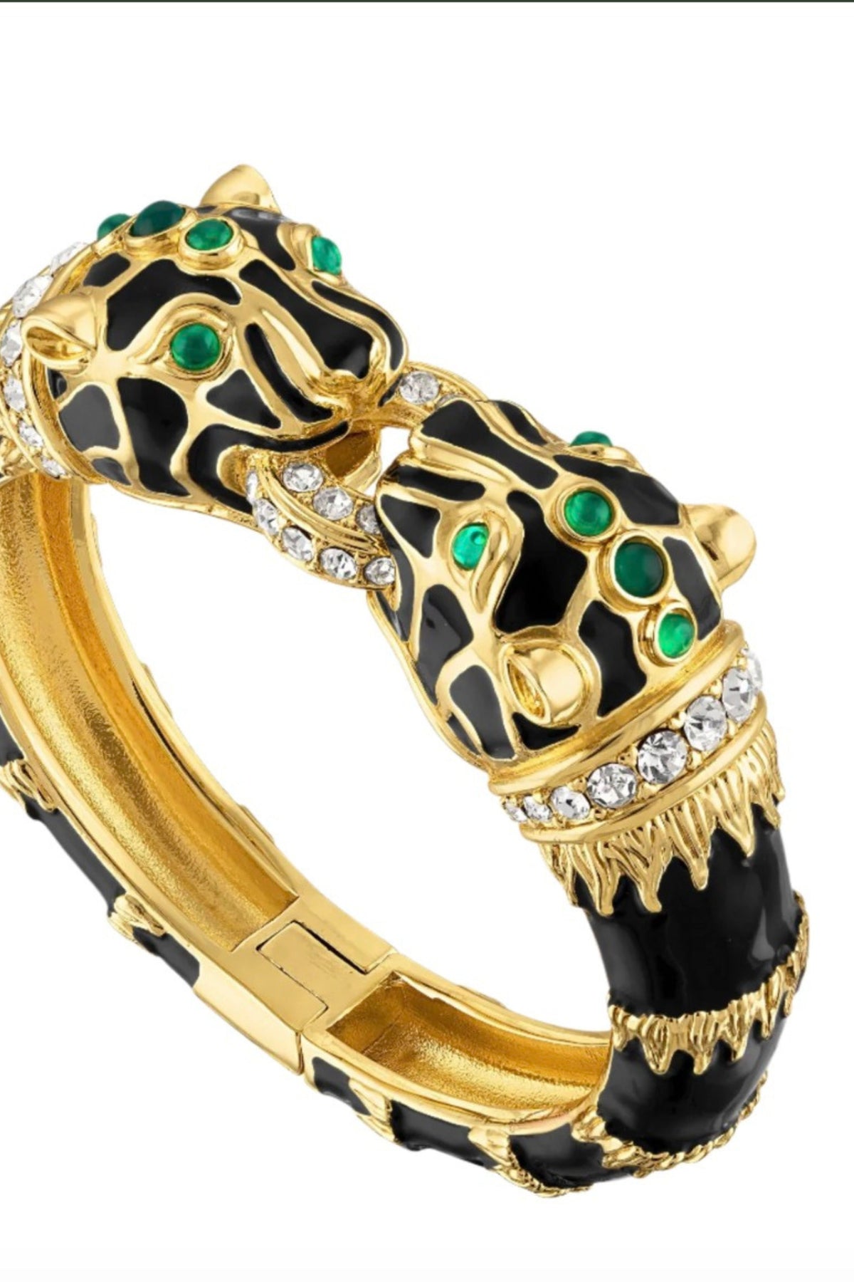 A gold-plated bangle bracelet featuring two stylized panther heads with black enamel, green emerald accents, and small clear crystals, shown on a plain white background.