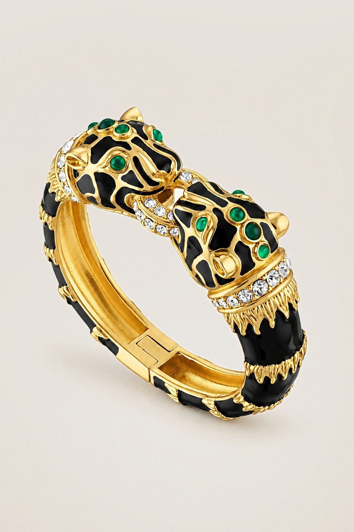Black Enamel Double Panther Bracelet in 18K gold plate over brass with black enamel, crystals and green glass cabochon eyes, on a warm greige backdrop.