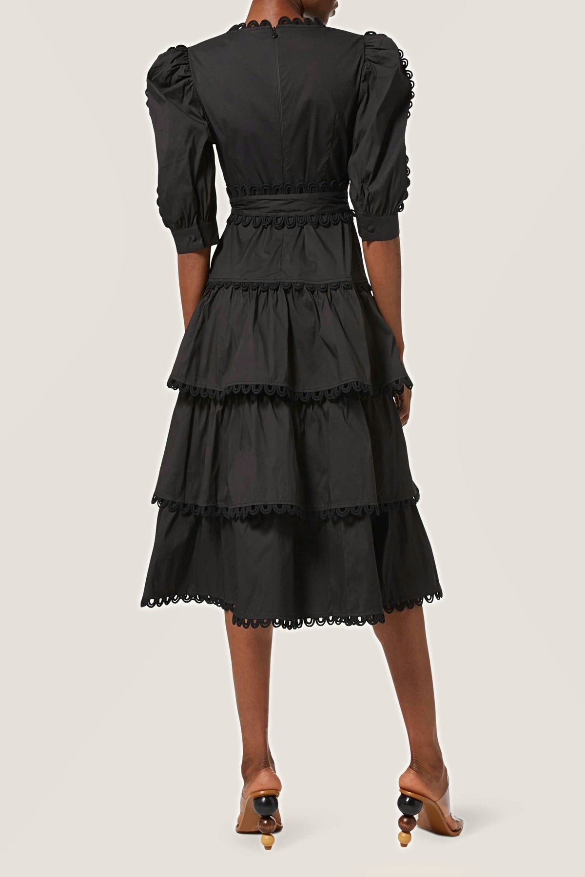 Back view of the black tiered midi dress showing the puff sleeves and tiered skirt.