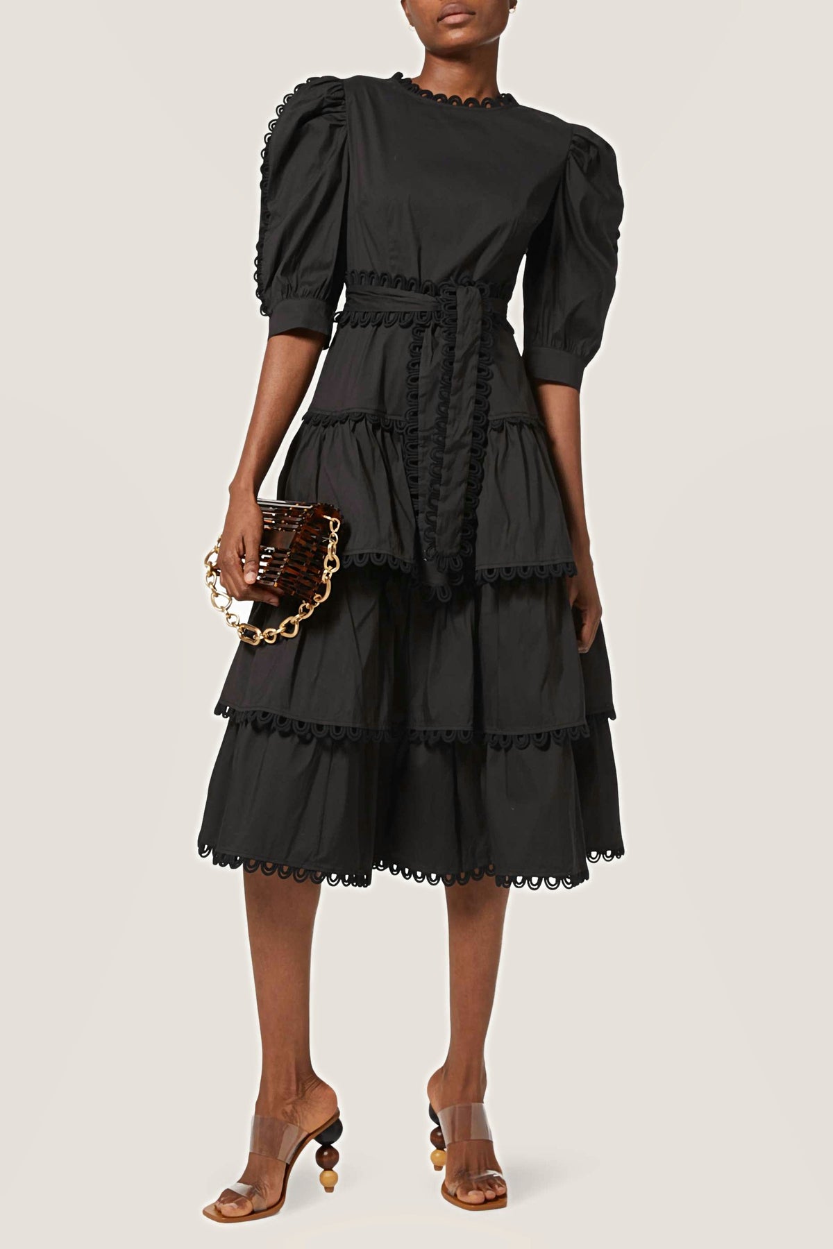 Three-quarter view of the black tiered midi dress with puff sleeves and a tie waist.