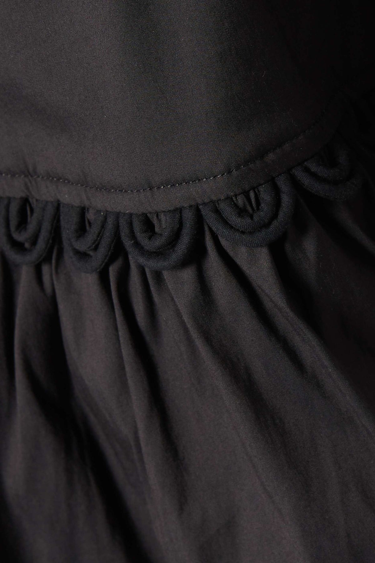 Macro close-up of the black looped cord trim on the cotton poplin.